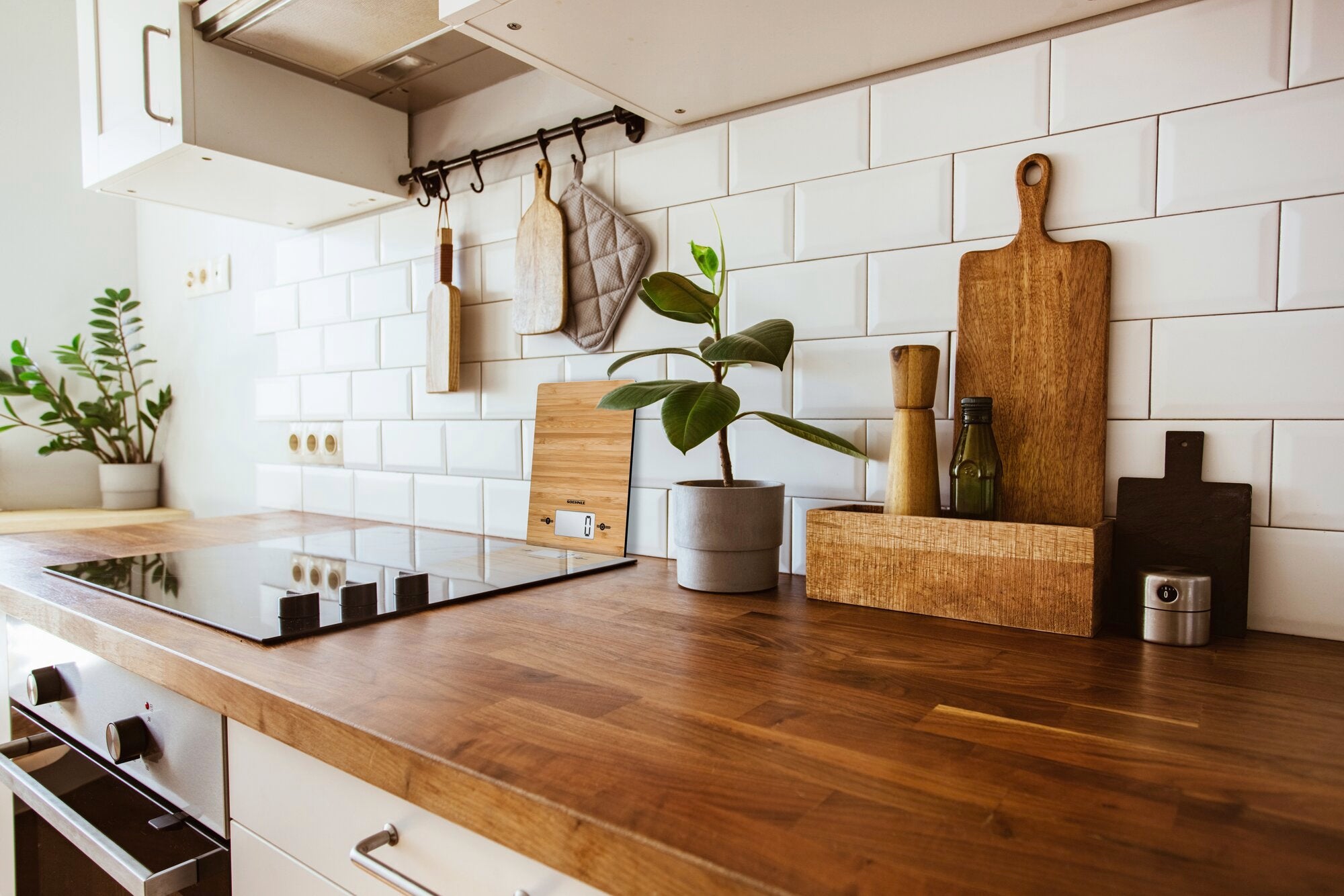 Digitale Küchenwaage Bamboo auf einer stilvollen Küchenarbeitsplatte aus Holz, umgeben von Schneidebrettern, Pflanzen und Küchenutensilien. Ideal für moderne Küchen.