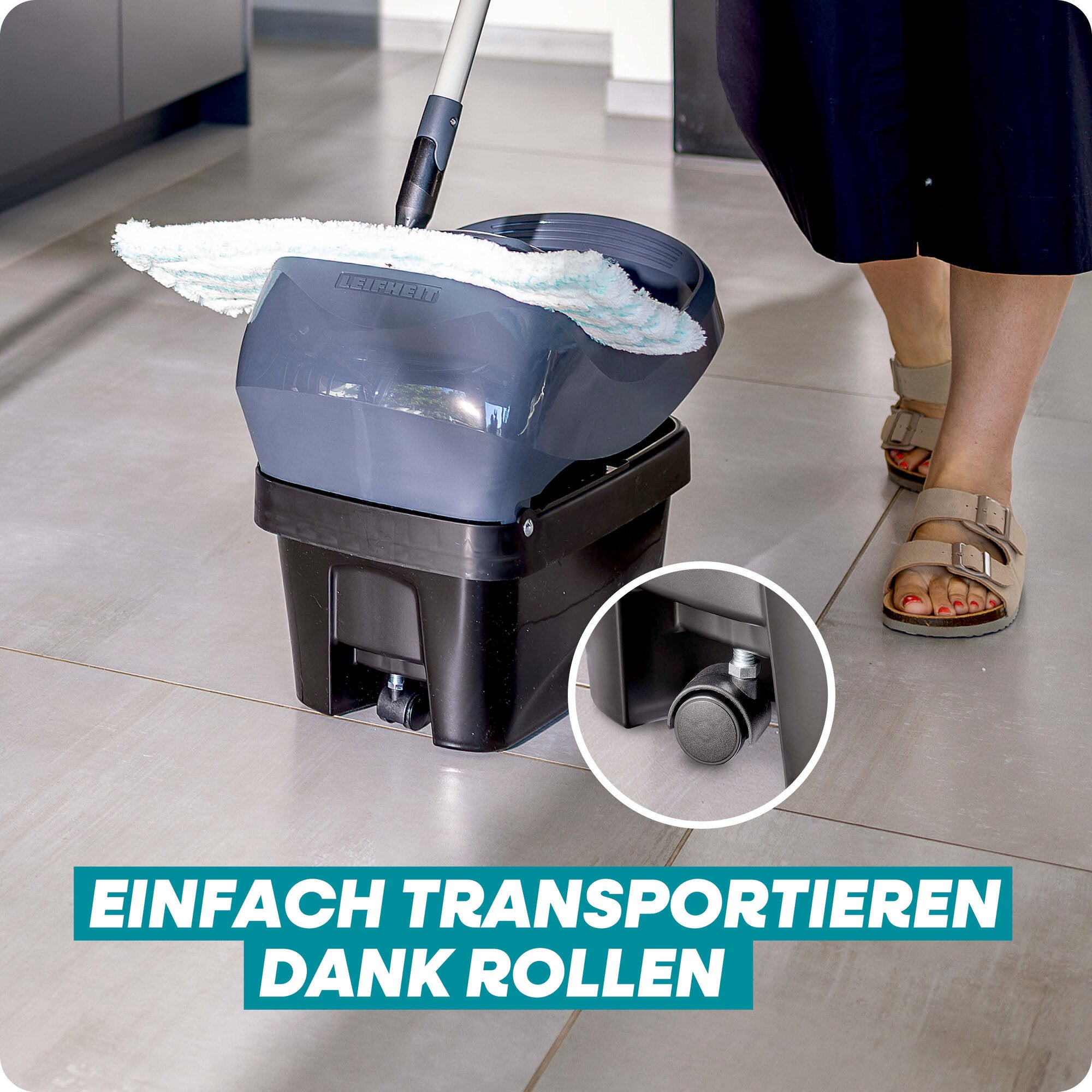 Leifheit Set Profi XL Mobile Black mit Wischbezug und Eimer auf Rollen im Einsatz auf Fliesenboden; die fahrbare Presse ermöglicht bequemes Transportieren ohne Anheben, neben den Füßen der Anwenderin.