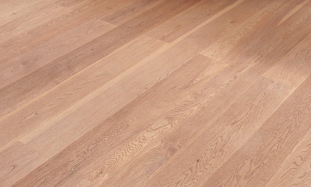 Heller Holzboden mit gleichmaessiger Maserung und langen Dielen, die diagonal ausgerichtet sind, in einem warmen Braunton.