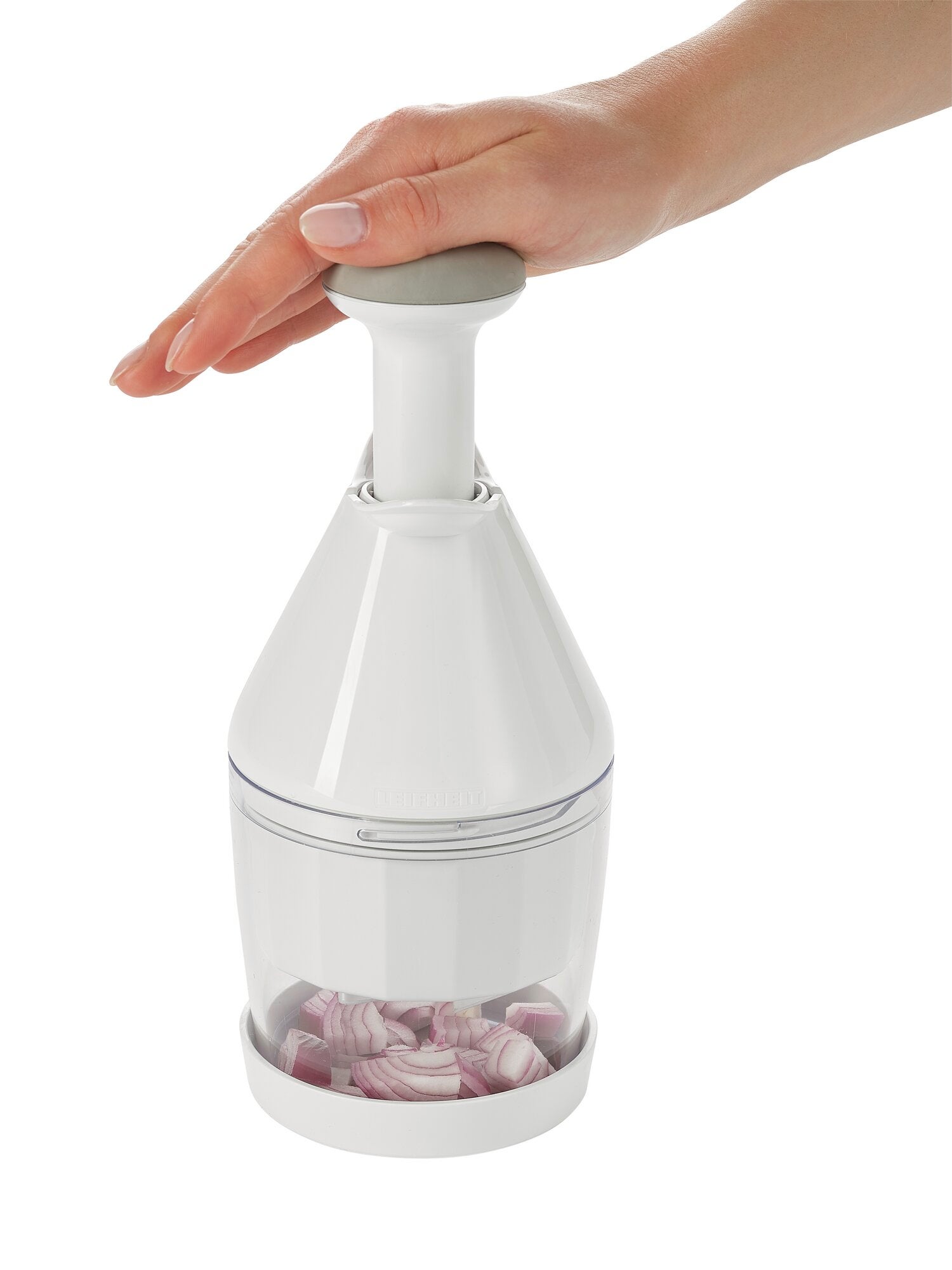 Een hand bedient een uien- en groentenhakker. De witte hakmolen hakt rode uien in een transparante bak. Ideaal om snel en gemakkelijk te hakken.