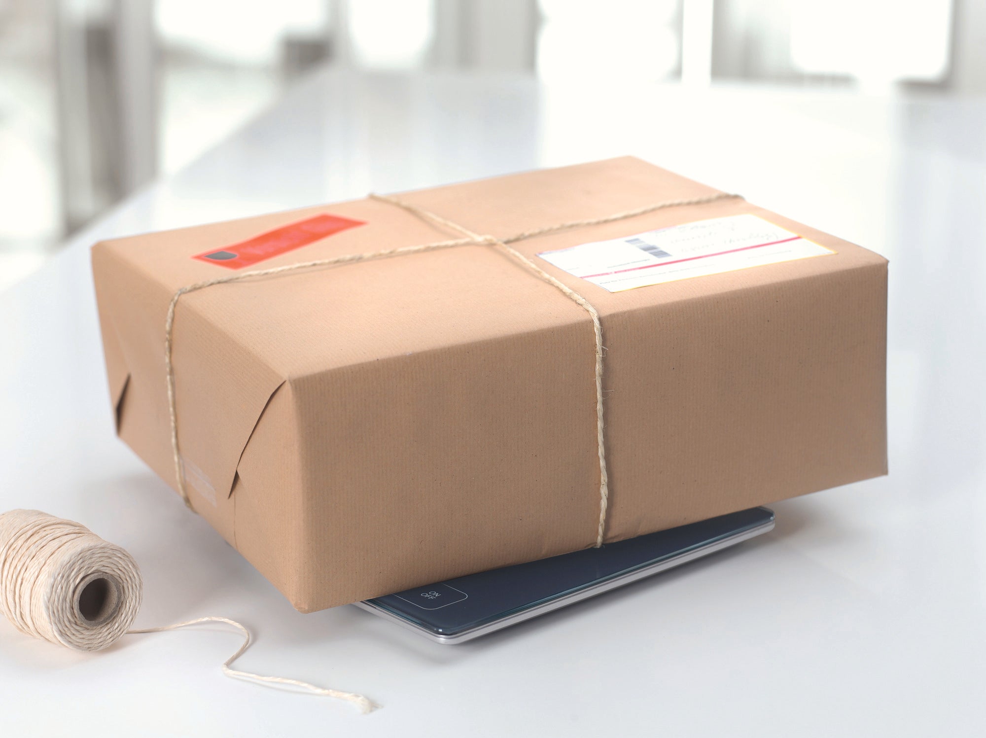 Ein Paket, das auf einer digitalen Küchenwaage liegt. Die Waage ist flach und modern gestaltet, ideal für präzises Wiegen in der Küche. Perfekt für den täglichen Gebrauch.