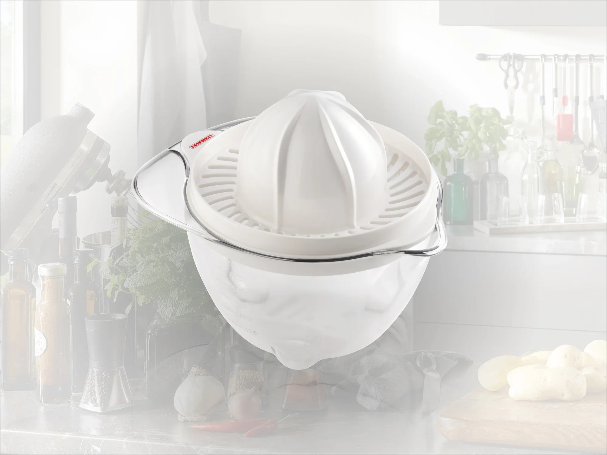 Saftpresse auf einer Küchenarbeitsplatte. Die weiße Kunststoffpresse hat einen integrierten Behälter und ist ideal zum Auspressen von Zitrusfrüchten. Im Hintergrund sind Küchenutensilien sichtbar.