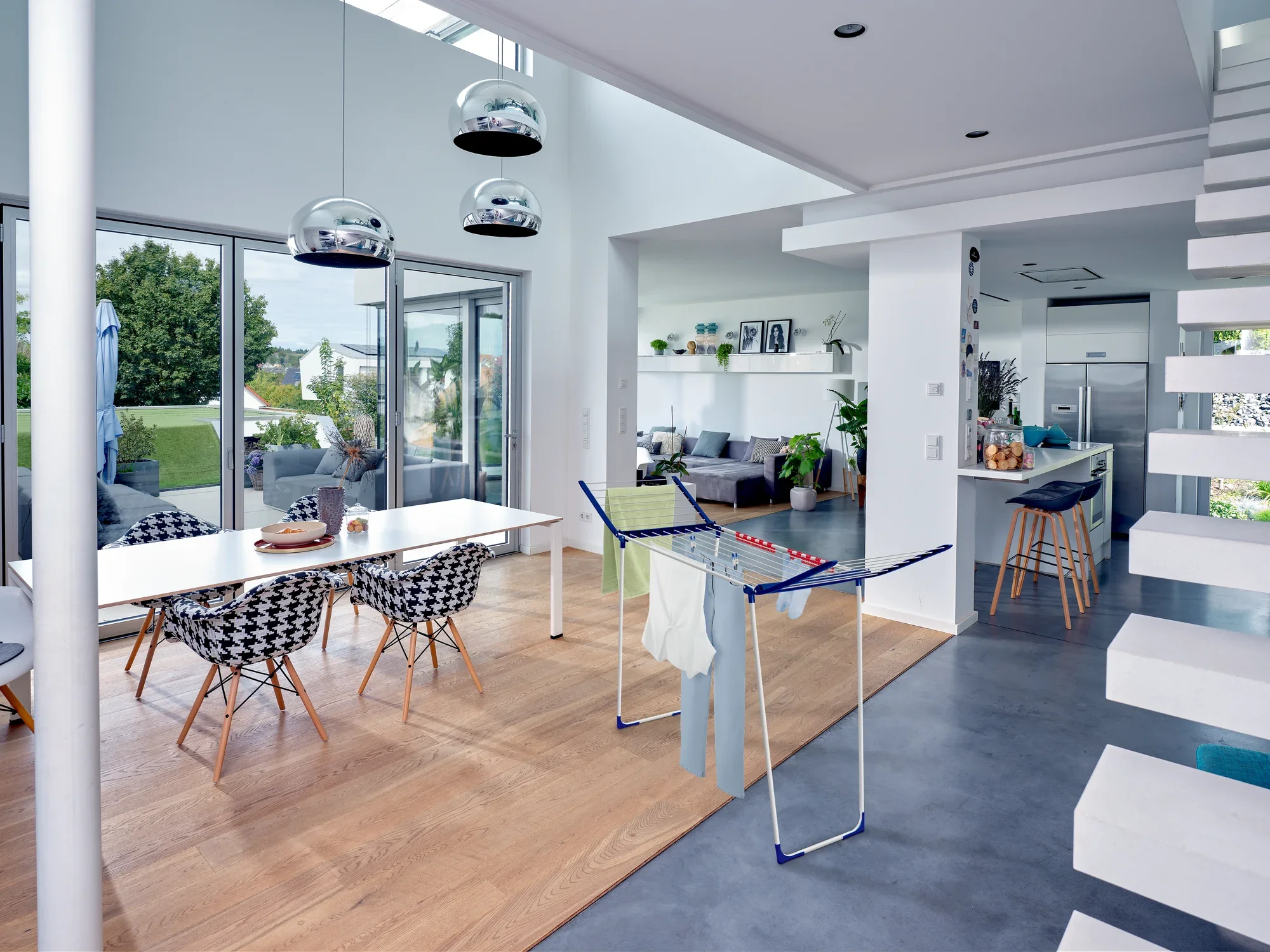 Ein moderner, lichtdurchfluteter Wohnraum mit einem Standtrockner Pegasus 180 Maxx im Vordergrund. Der Raum ist stilvoll eingerichtet mit einem Esstisch und großen Fenstern.