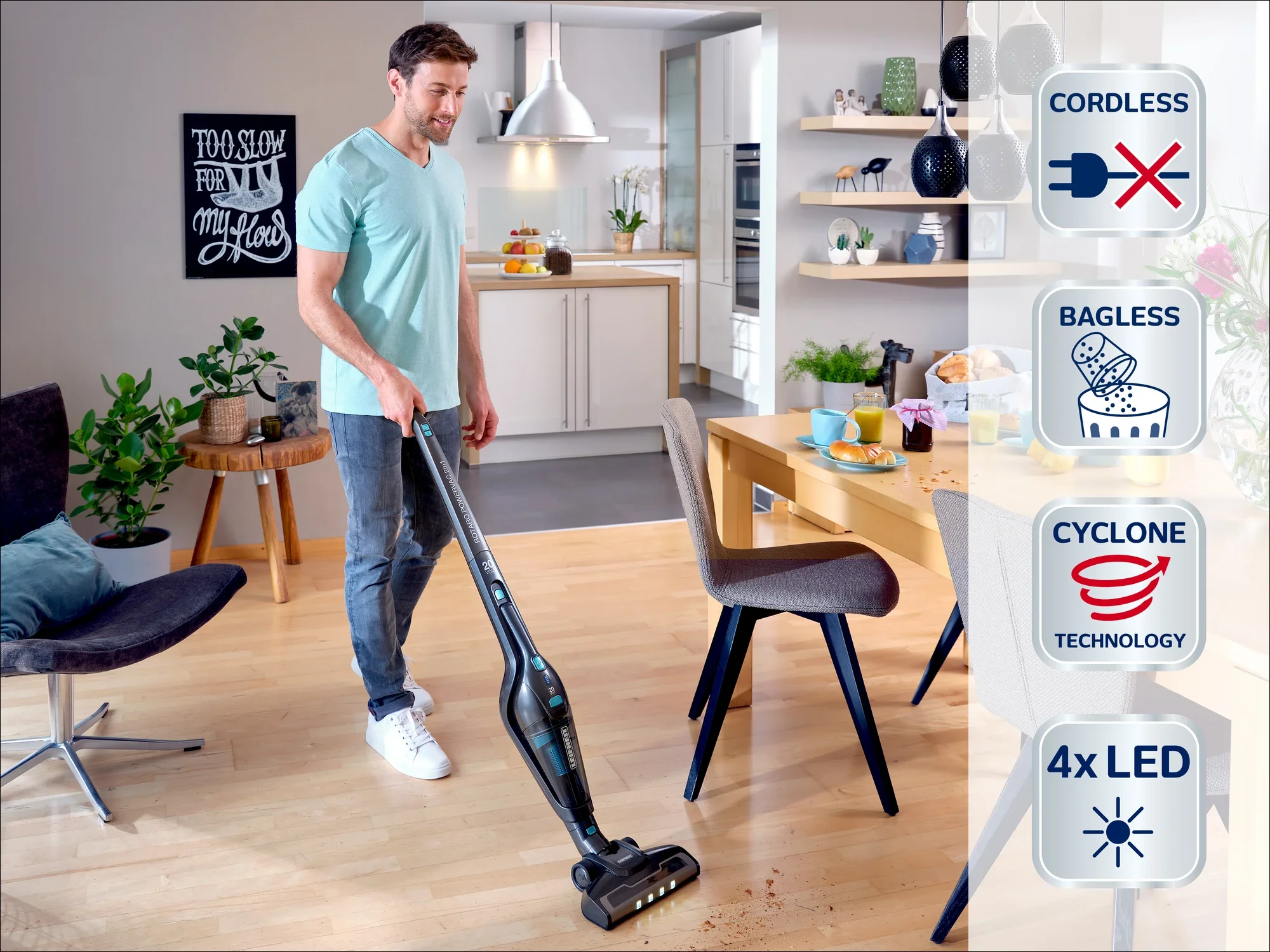 Un homme utilise un aspirateur sans fil et sans sac avec technologie cyclonique dans un salon moderne. L'aspirateur est équipé de 4 LED pour une meilleure visibilité.