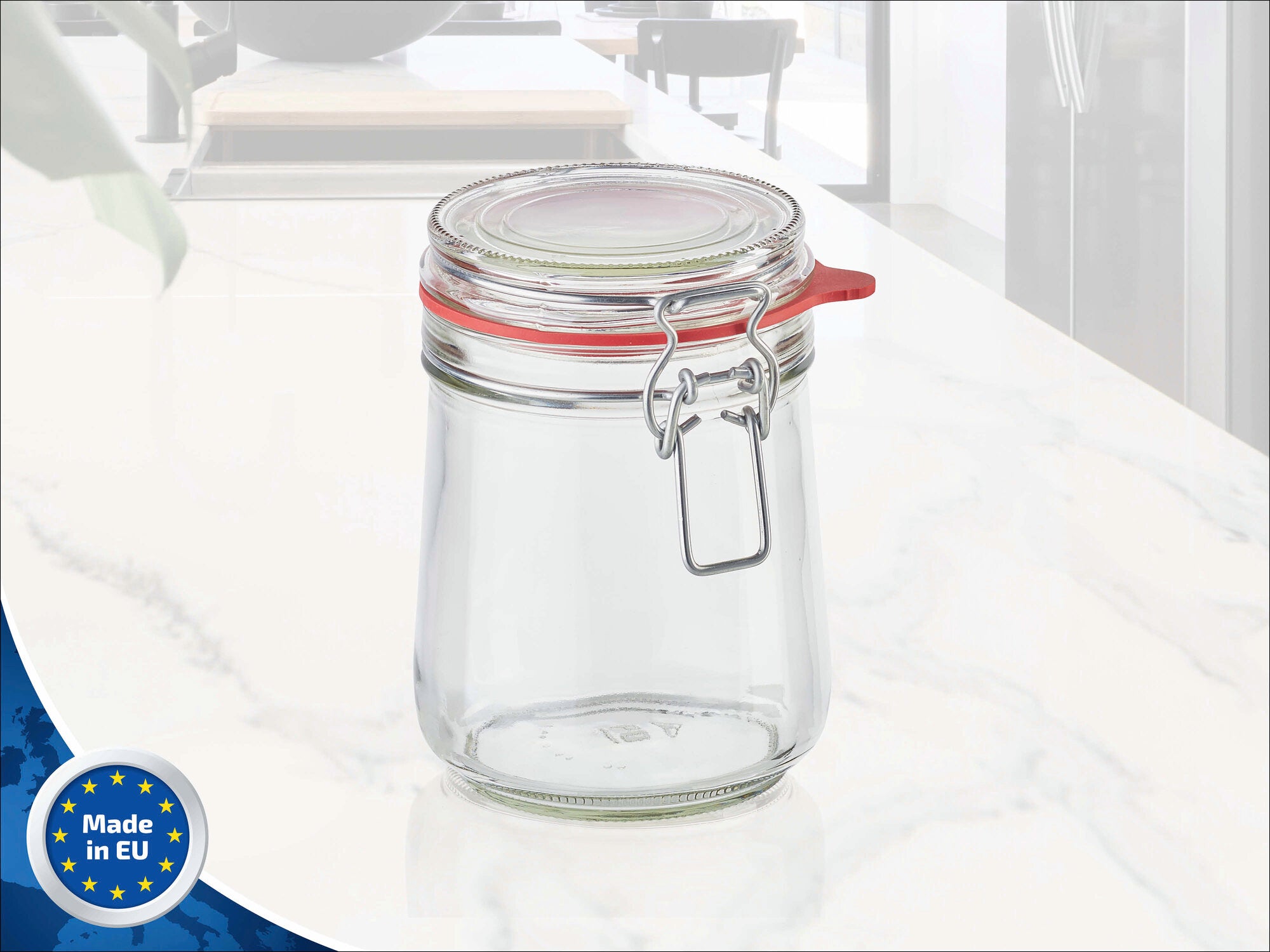 Drahtbügelglas von Leifheit mit einem Fassungsvermögen von 800 ml. Das Glas hat einen roten Gummiring und einen Metallverschluss. Ideal zum Aufbewahren von Lebensmitteln. Im Hintergrund ist eine moderne Küche zu sehen. Made in EU.