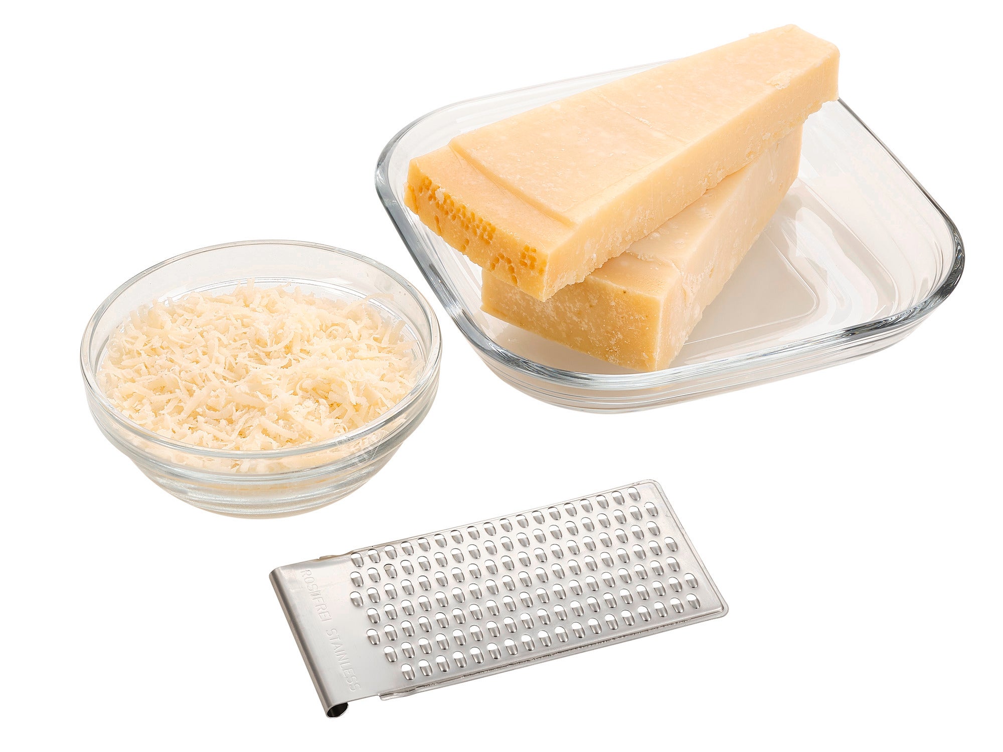 An all-purpose grater with four functions lies next to a bowl of grated cheese and three pieces of cheese. Ideal for grating cheese for various dishes.