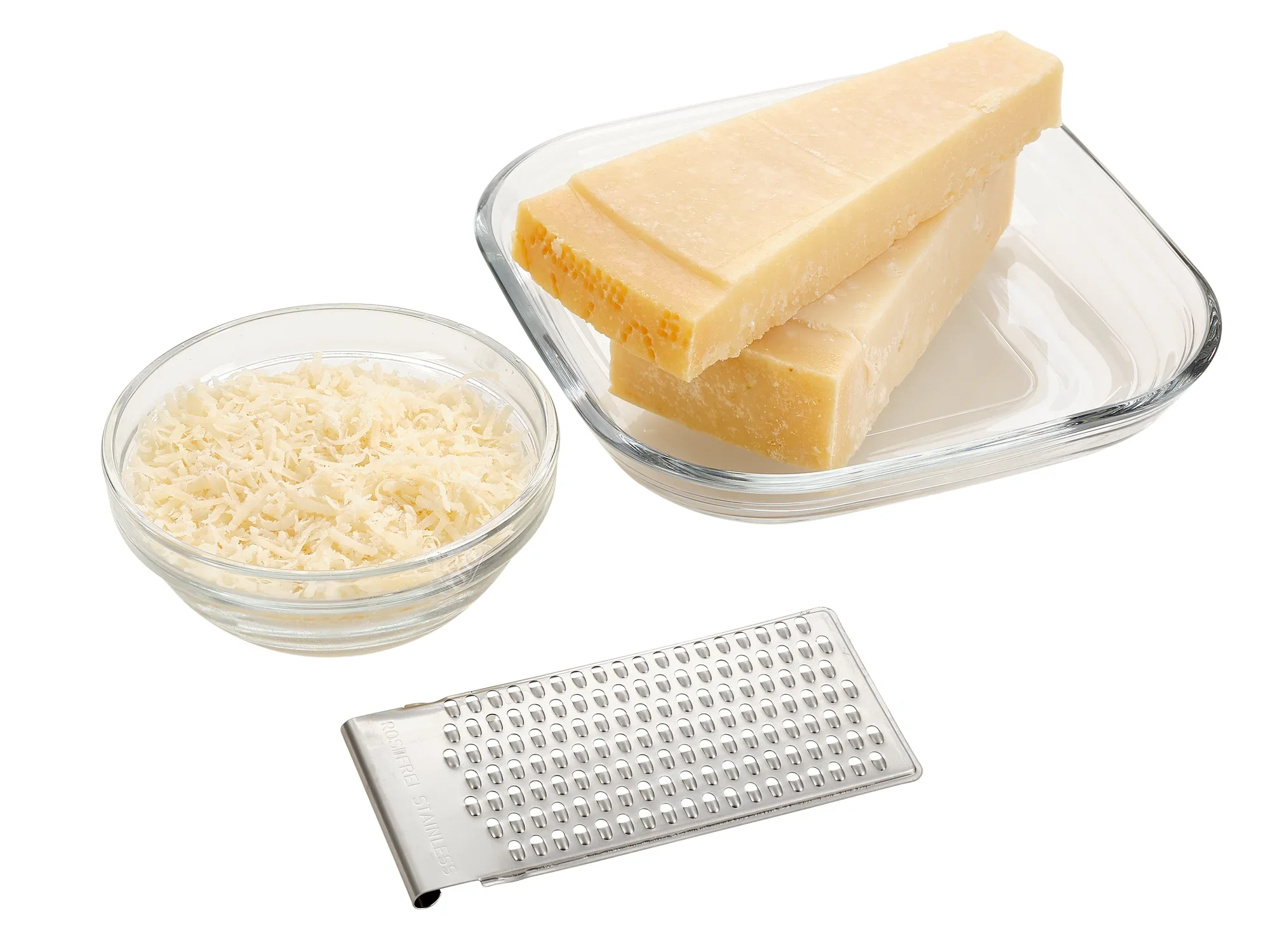 Een allesrasp met vier functies ligt naast een kom geraspte kaas en drie stukken kaas. Ideaal voor het raspen van kaas voor verschillende gerechten.