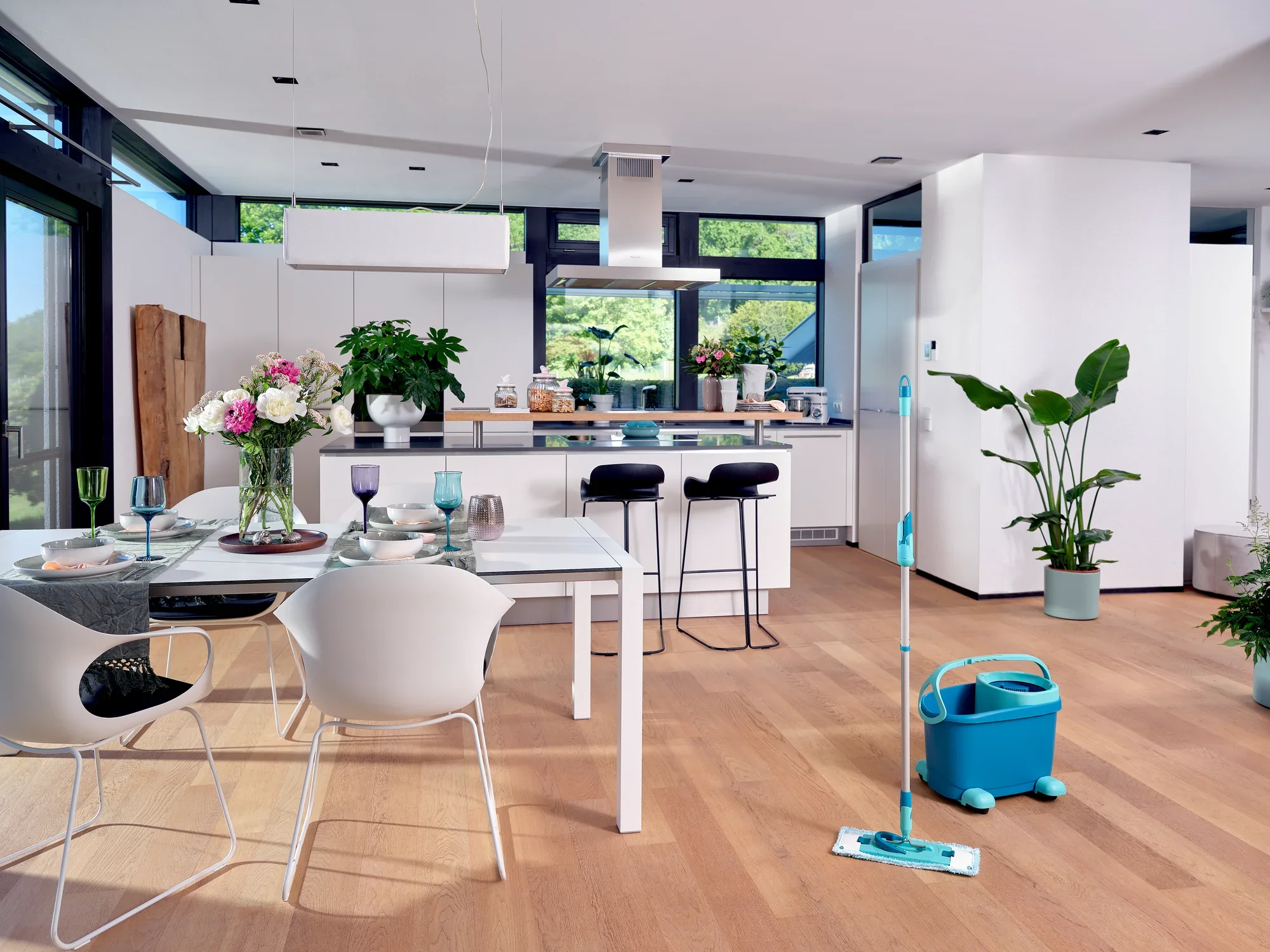 De CLEAN TWIST M Ergo Set staat in een moderne, lichtgekleurde keuken. De dweil en emmer staan klaar om schoongemaakt te worden om de houten vloer vlekkeloos te houden. Planten en decoraties maken de stijlvolle sfeer compleet.