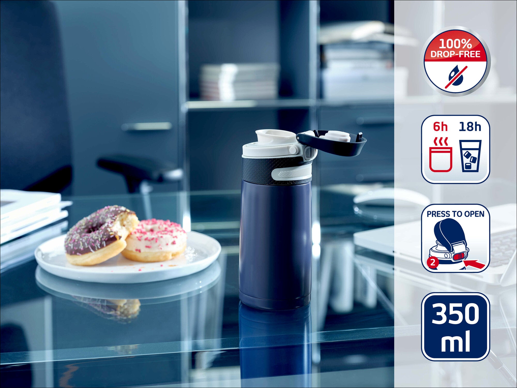 Leifheit Isolierbecher 350 ml in Dunkelblau auf einem Glastisch im Büro, neben einem Teller mit zwei Donuts. Seitlich zeigen Symbole 100 % auslaufsicher, 6 h warm, 18 h kalt und Druckknopf zum Öffnen.