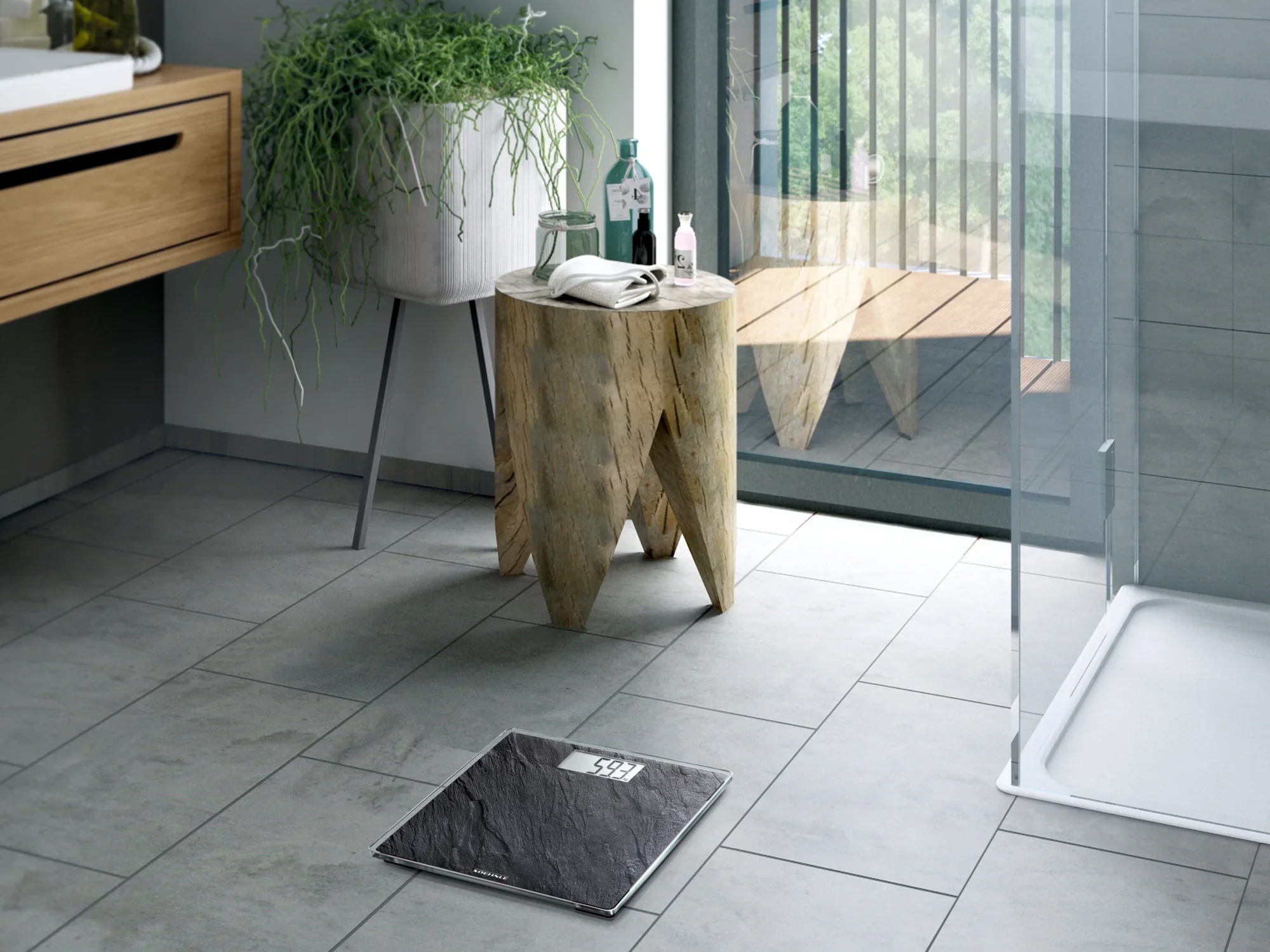 Waga łazienkowa Digital Style Sense Compact 300 Nature Edition w kolorze łupkowym prezentuje się na podłodze nowoczesnej łazienki. Obok wagi znajduje się drewniany stolik z roślinami i produktami do pielęgnacji.