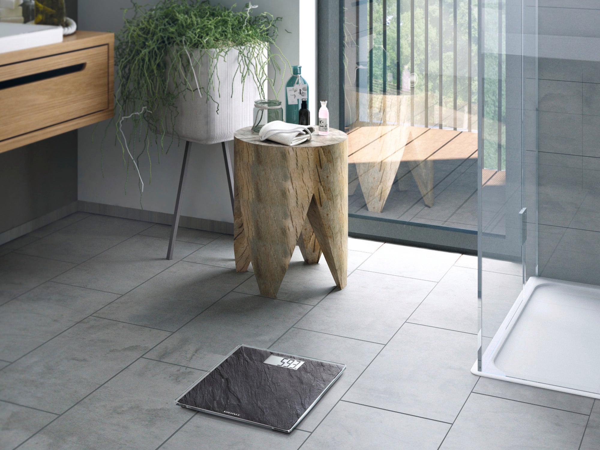 Personenwaage digital Style Sense Compact 300 Nature Edition in Schieferoptik auf einem modernen Badezimmerboden. Neben der Waage steht ein Holztisch mit Pflanzen und Pflegeprodukten.