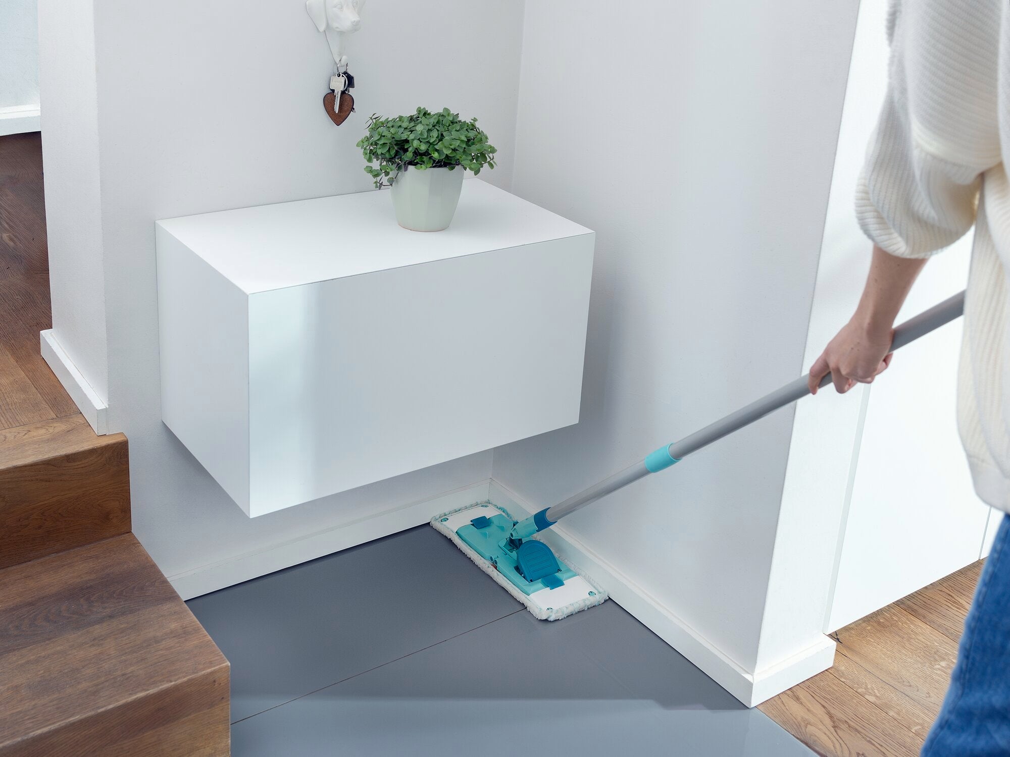 Une personne nettoie le sol dans une pièce moderne et lumineuse avec le kit POWER CLEAN. La serpillière glisse sans effort sur le carrelage pour éliminer la poussière et la saleté.