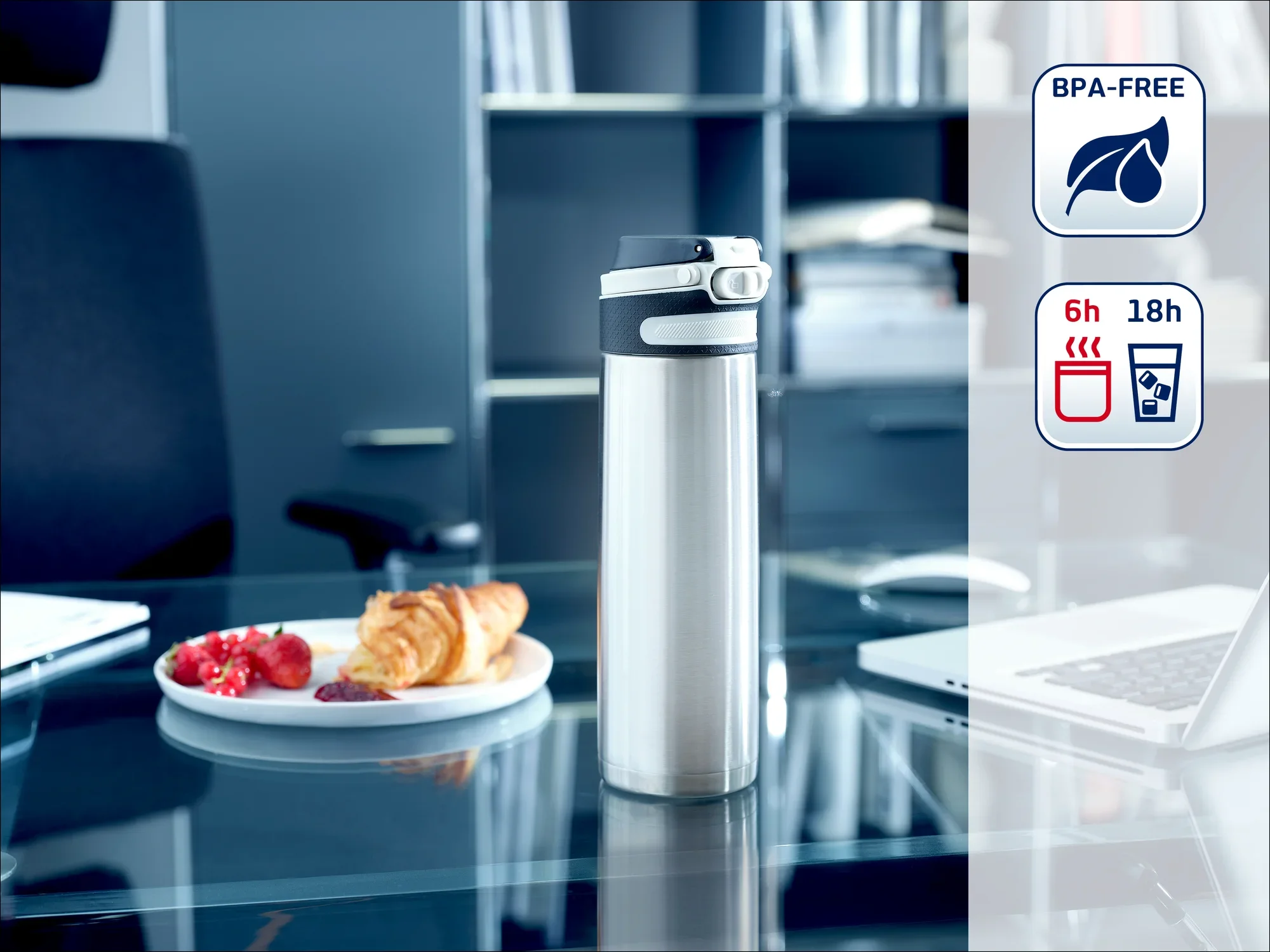 Termos ze stali nierdzewnej stoi na nowoczesnym biurowym stole obok talerza z herbatnikami. W tle widoczne są półki. Butelka jest wolna od BPA i utrzymuje napoje gorące przez 6 godzin, a zimne przez 18 godzin.