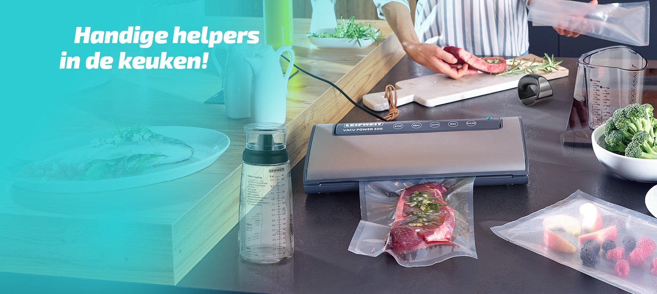 Een keuken met een vacuuemmachine, verse kruiden, gesneden vlees en groenten.