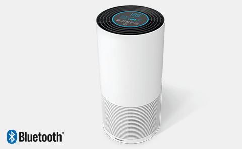 Ein zylindrischer, weisser Luftreiniger mit einem schwarzen, digitalen Display und Bluetooth-Symbol auf grauem Hintergrund.