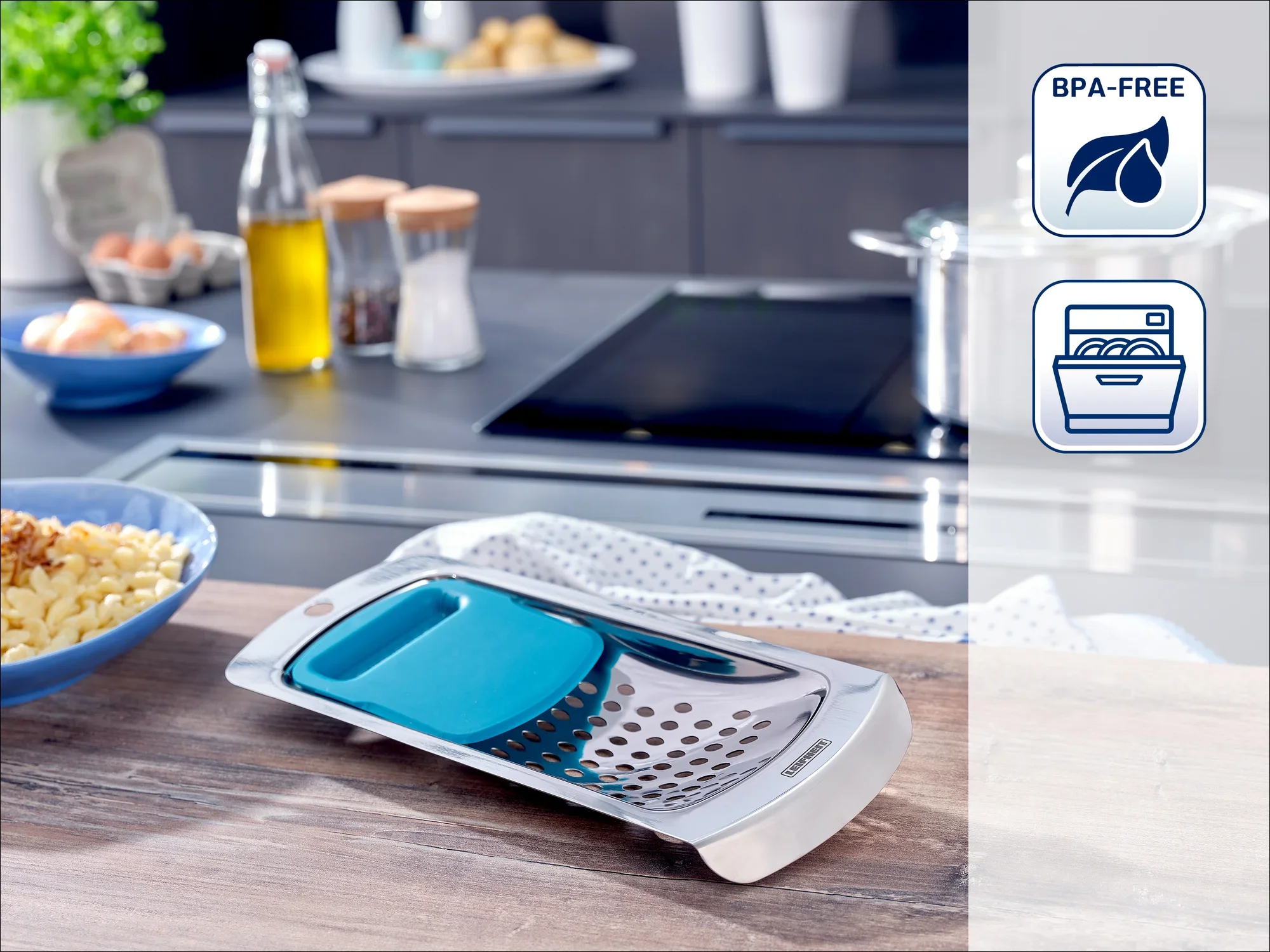 Une mandoline de cuisine de haute qualité est posée sur un plan de travail moderne. Des épices et des bouteilles d'huile sont visibles à l'arrière-plan. La mandoline est sans BPA et passe au lave-vaisselle.