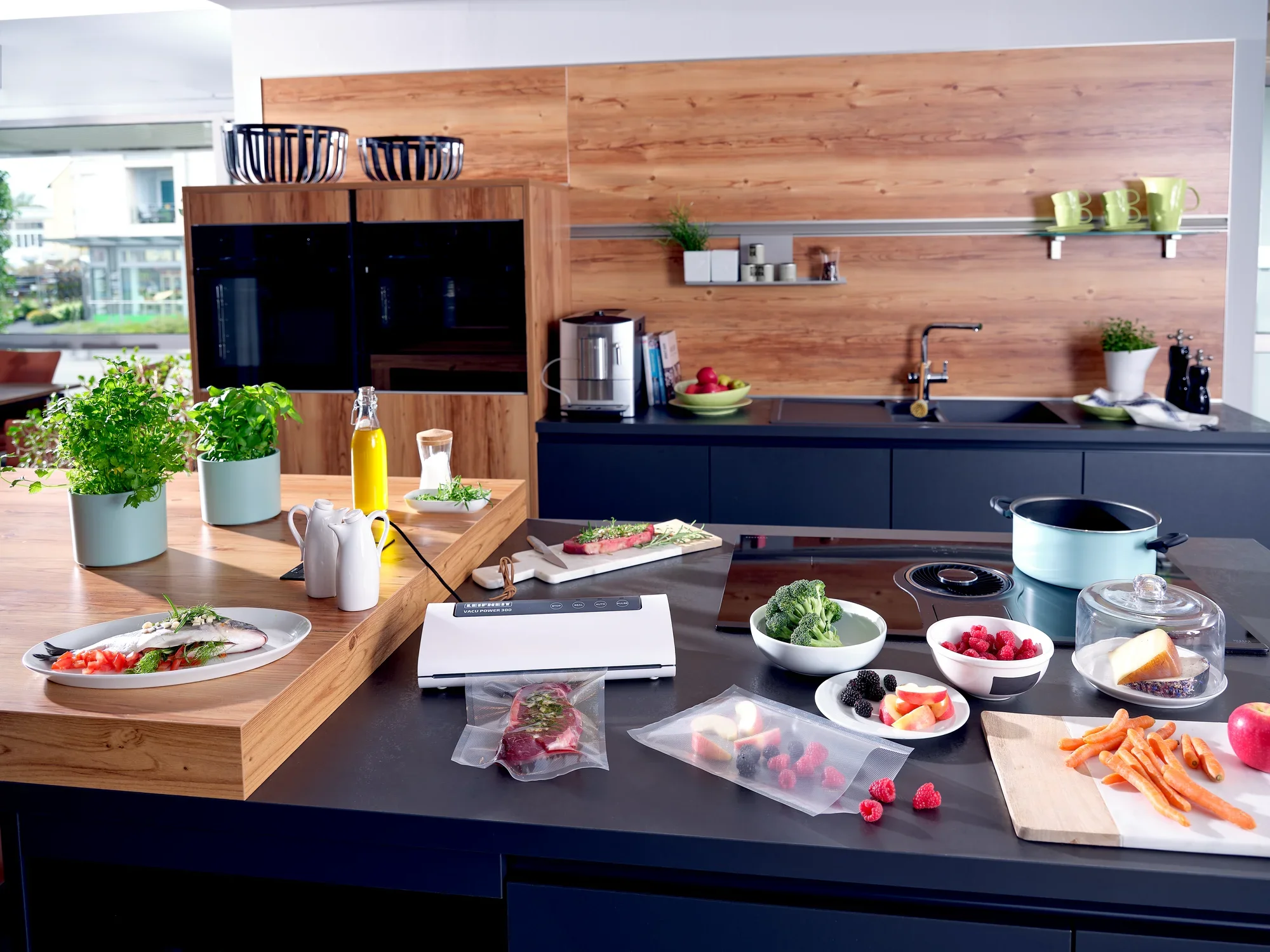 Dans une cuisine moderne, la machine sous vide Vacu Power 300 est posée sur le plan de travail. Entourée d'ingrédients frais tels que des légumes et des fruits, elle démontre sa polyvalence et son efficacité.