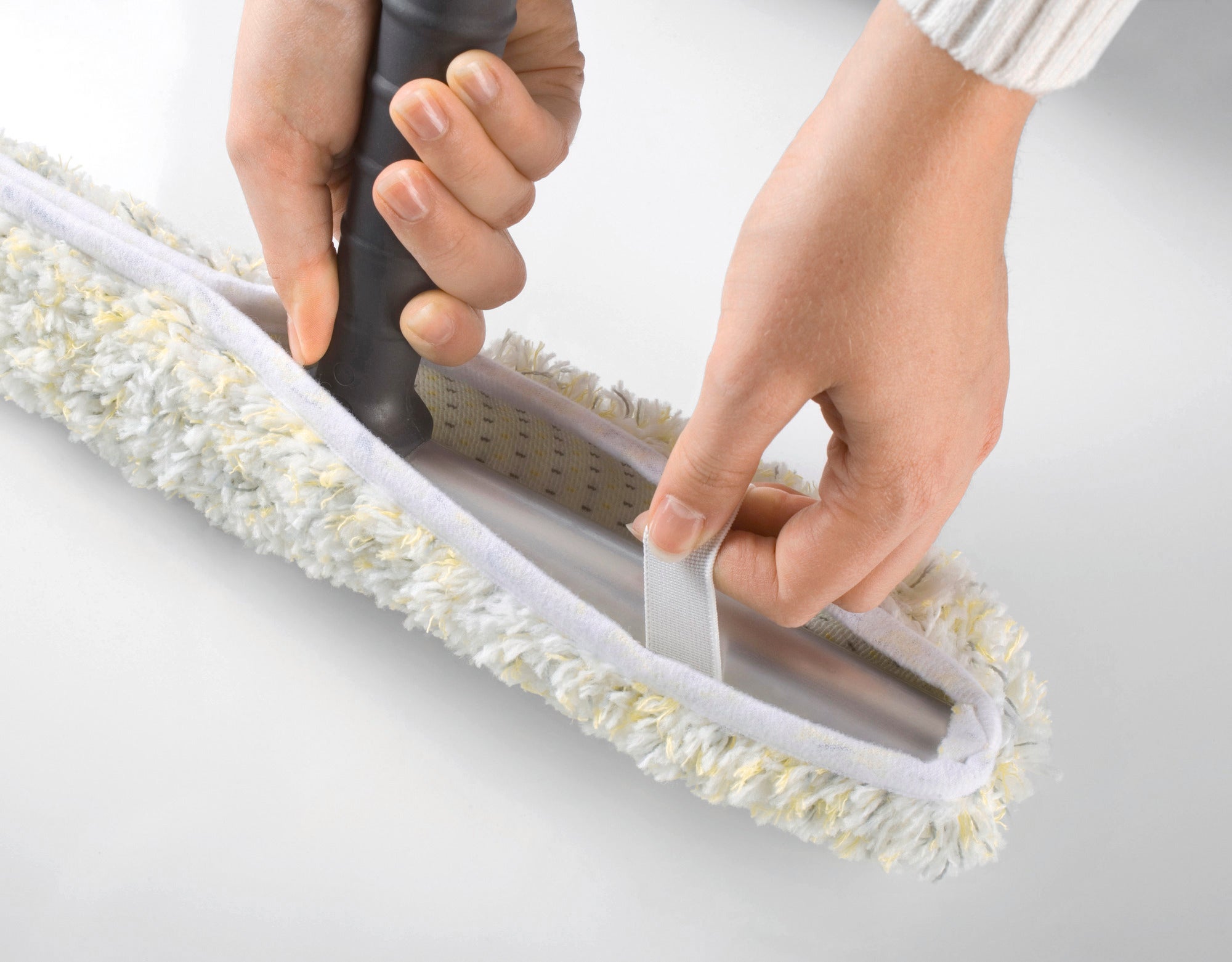 Eén paar handen bevestigt een Professional afdekzeil met enkele was van 45 cm aan een reinigingsapparaat. De overtrek heeft een donzig, wit oppervlak met gele accenten.