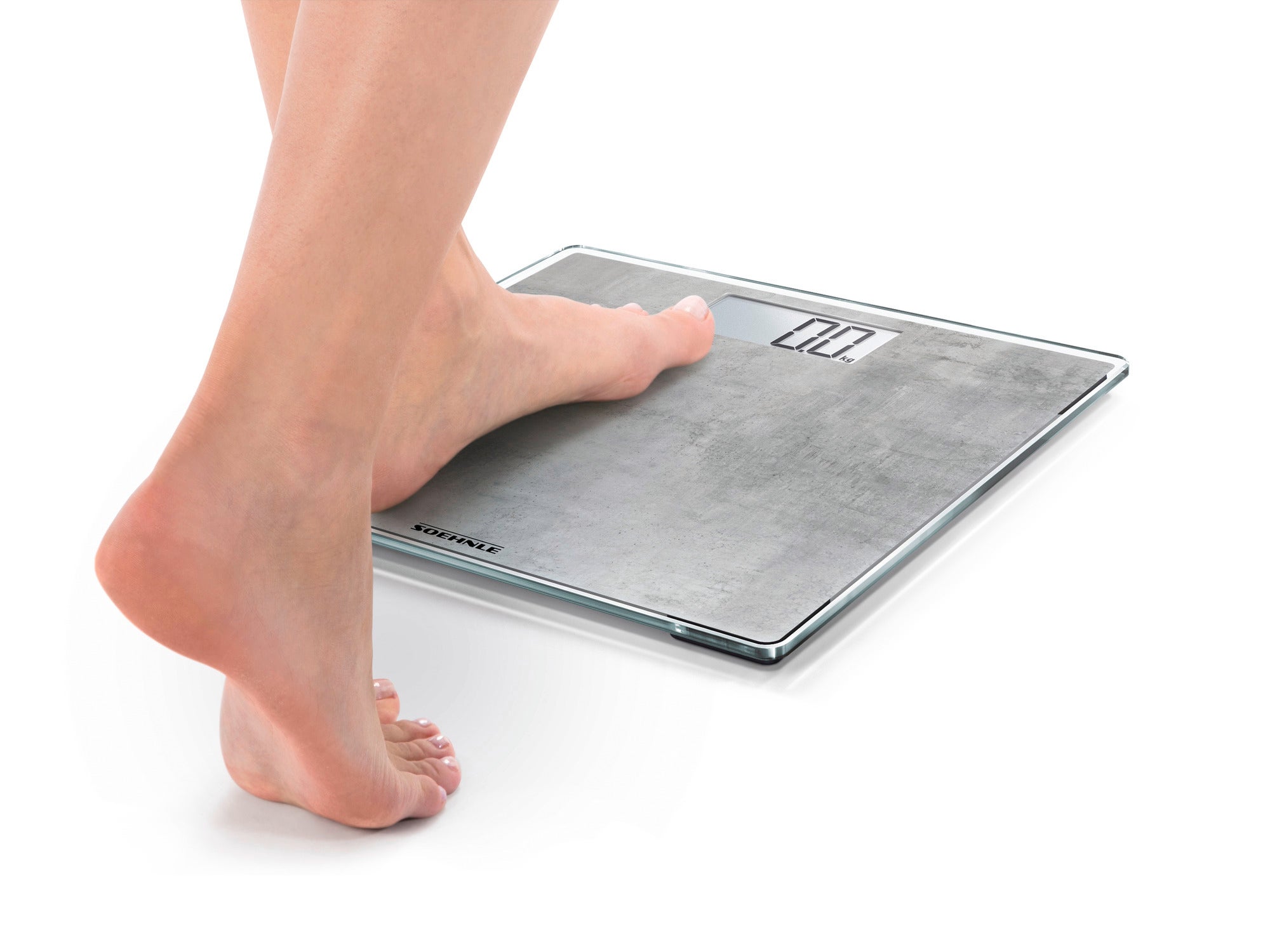 A person steps onto the Style Sense Compact 300 Nature Edition digital bathroom scale in concrete look. The scale has a modern design and a clear display.