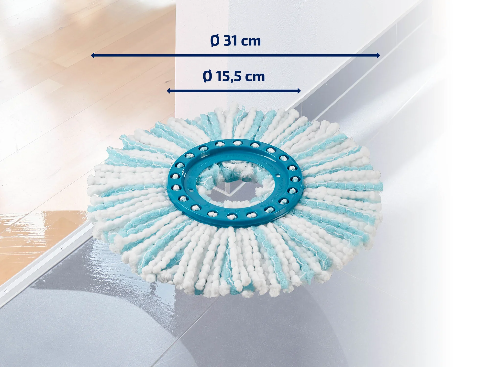 Un accesorio redondo para fregona con un diámetro de 31 cm y un anillo interior de 15,5 cm sobre un suelo brillante. El accesorio tiene rayas blancas y azules.