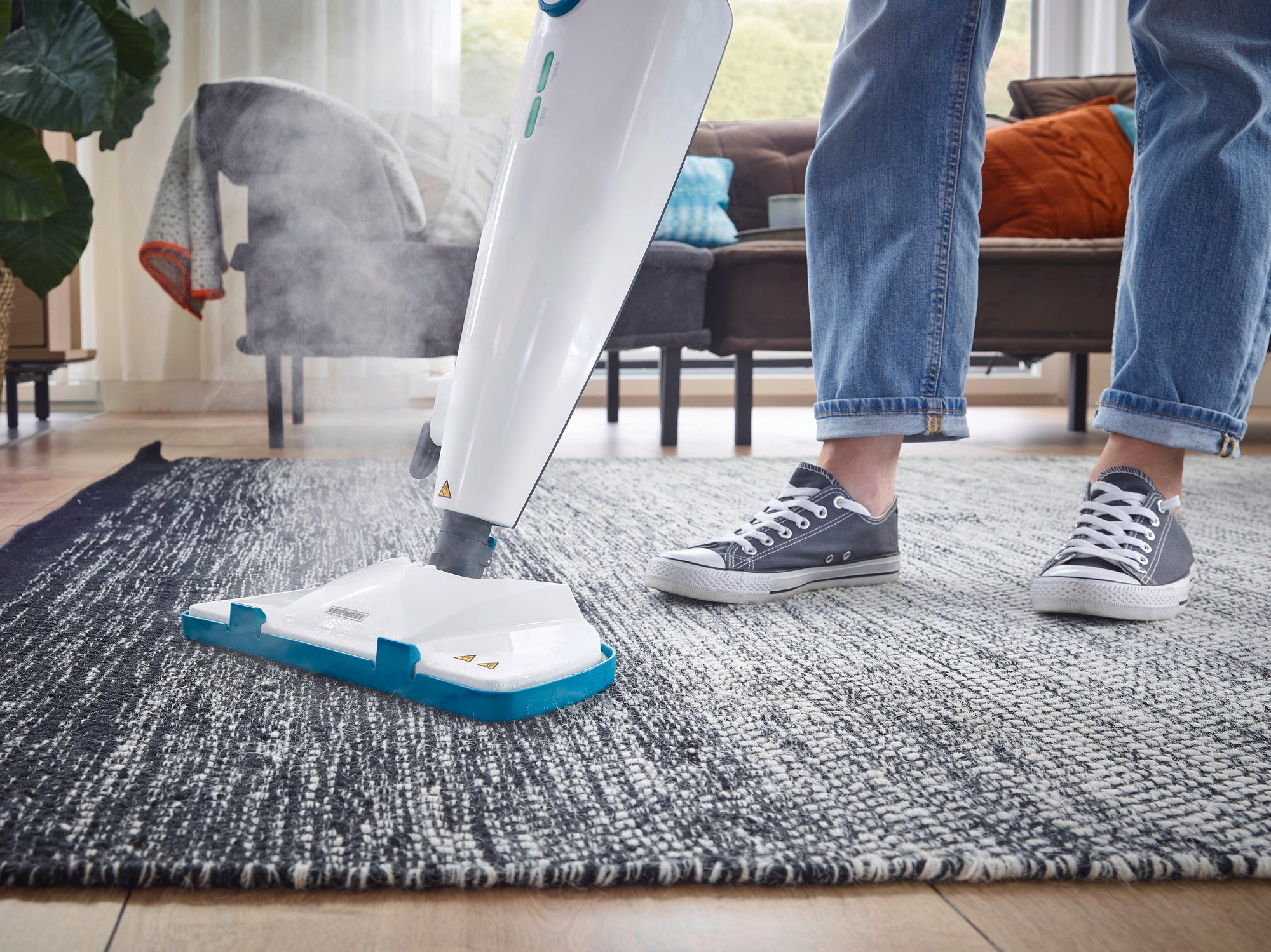 Dampfreiniger CleanTenso Power in Aktion auf einem Teppich. Eine Person bedient das Gerät, während Dampf austritt, um den Boden gründlich zu reinigen.
