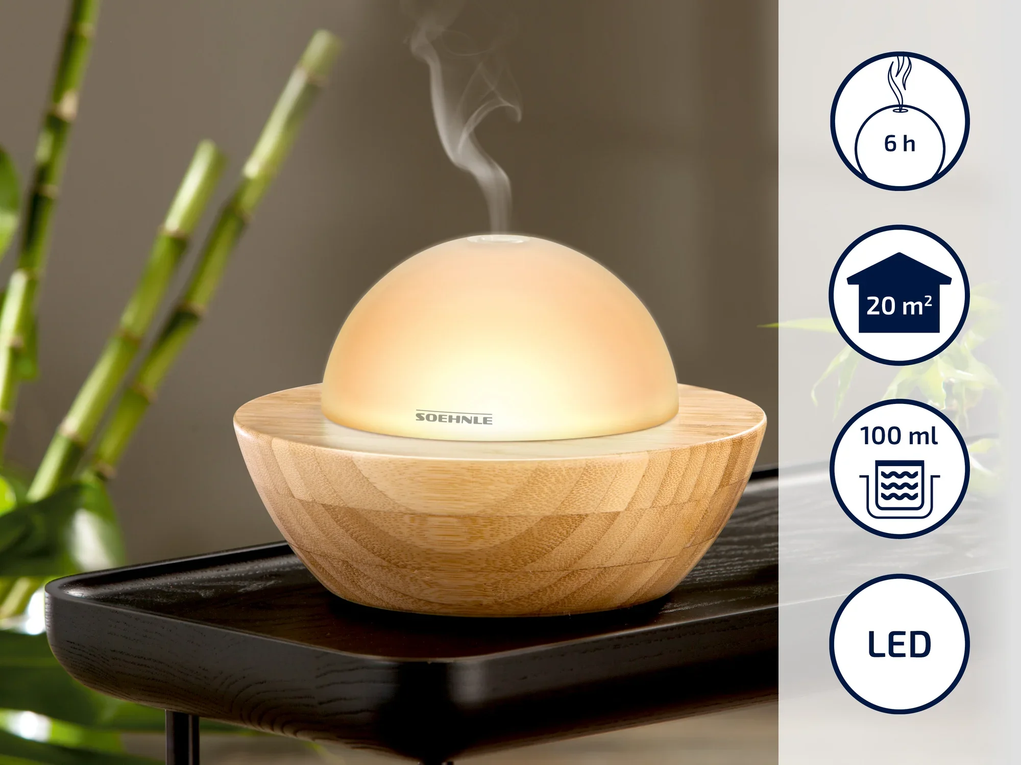 A round Soehnle aroma diffuser made of wood and glass on a table. It emits steam and is suitable for rooms up to 20 m². Running time: 6 hours, capacity: 100 ml, LED lighting.