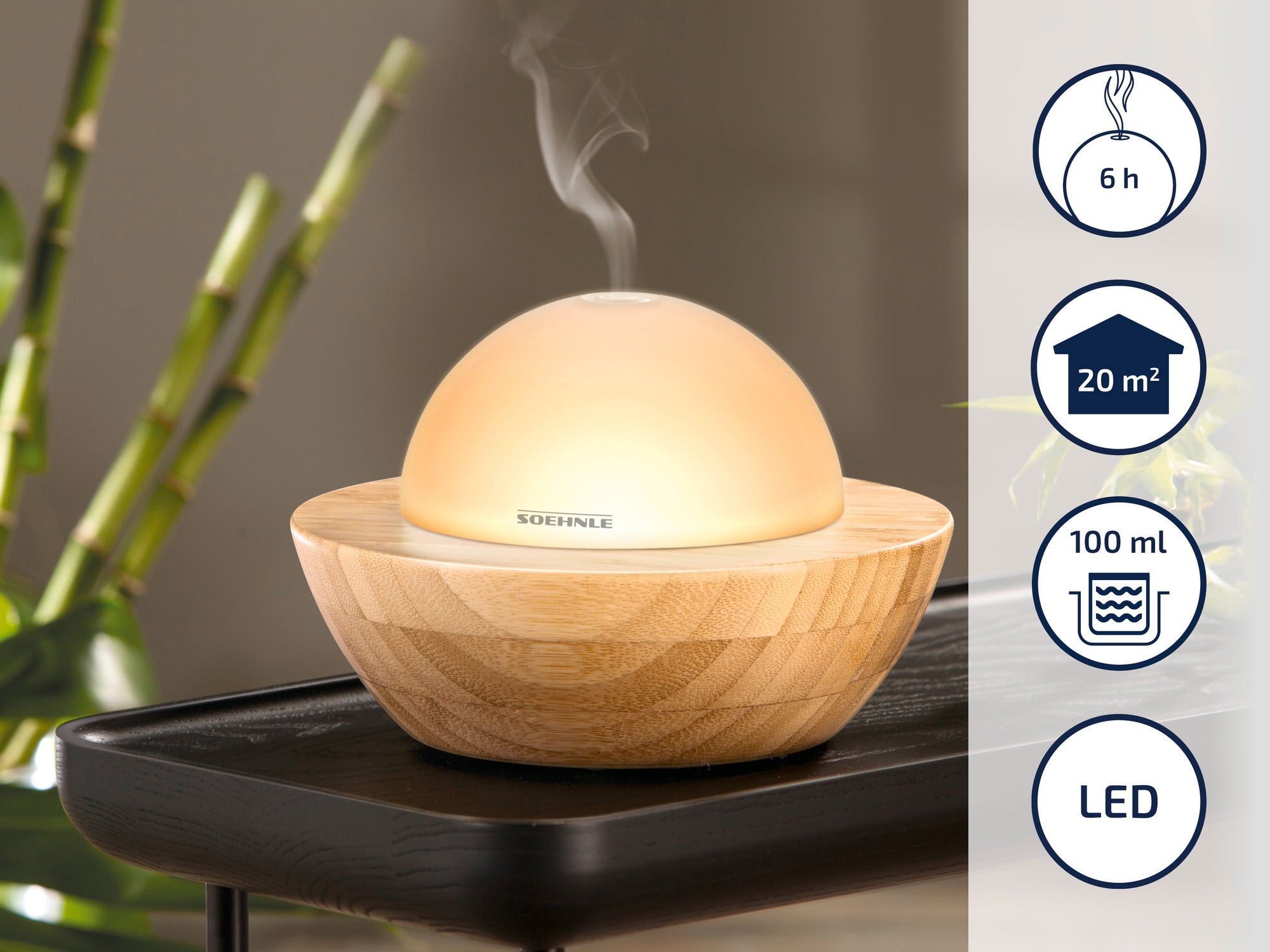Een ronde Soehnle aromaverstuiver van hout en glas op een tafel. Hij geeft stoom af en is geschikt voor ruimtes tot 20 m². Looptijd: 6 uur, inhoud: 100 ml, LED-verlichting.