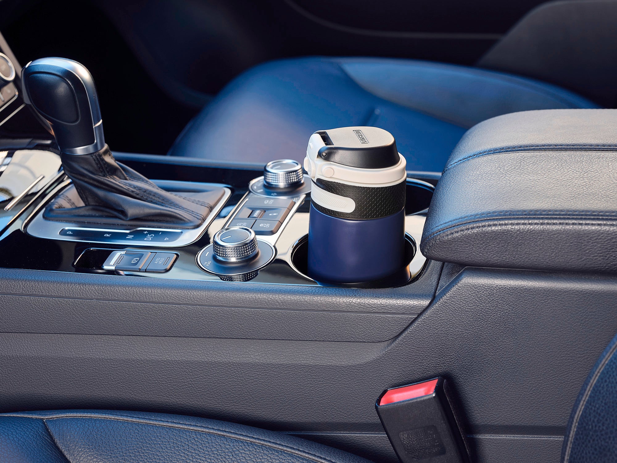 Isolierbecher Flip 350ml in Dunkelblau, platziert in einem Autohalter. Der Becher hat einen praktischen Deckel und passt perfekt in die Mittelkonsole eines Fahrzeugs.