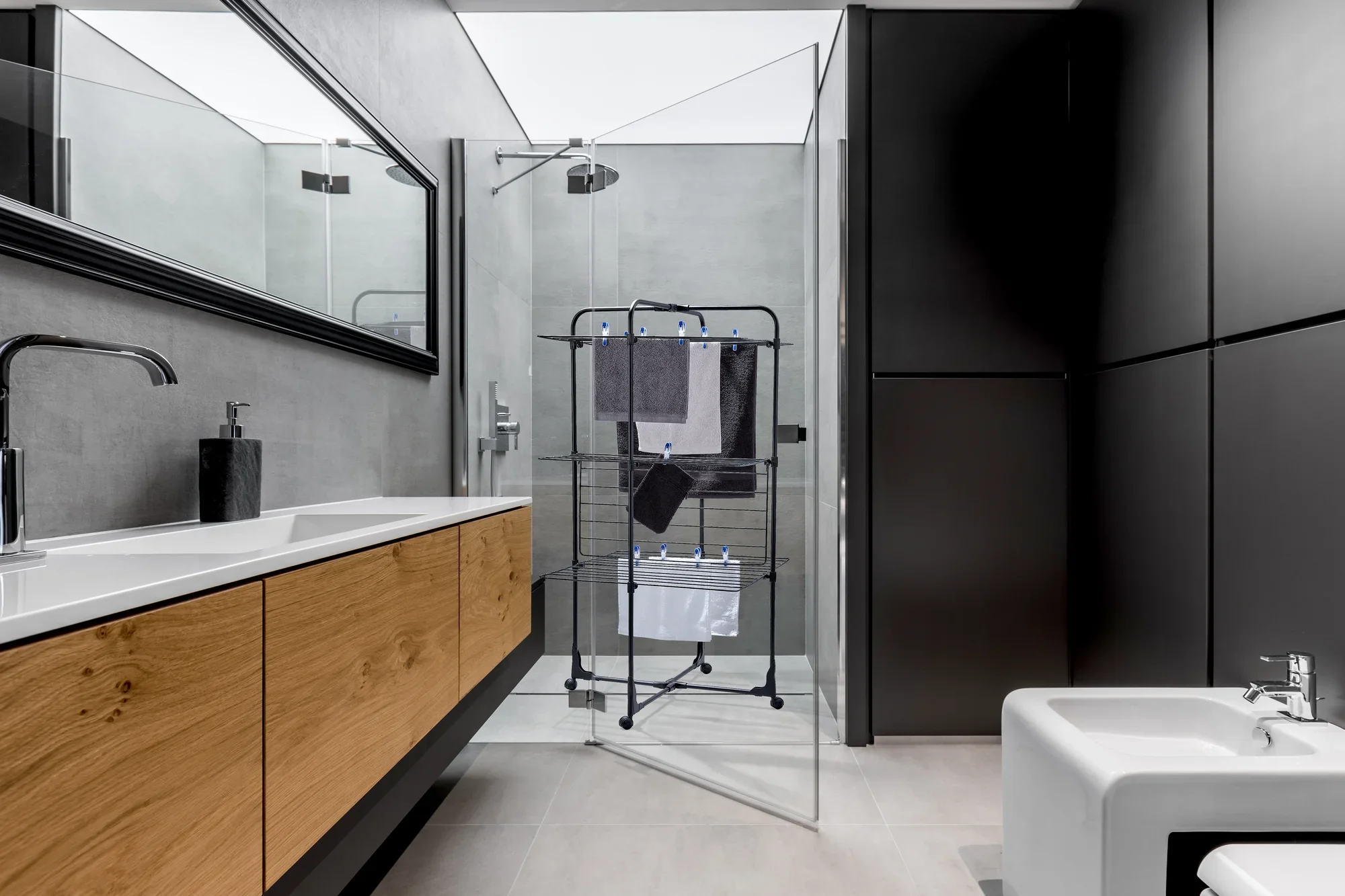 Classic Tower 270 tower dryer in a modern bathroom with glass shower and wooden washbasin. The dryer is compact and offers space for several towels.