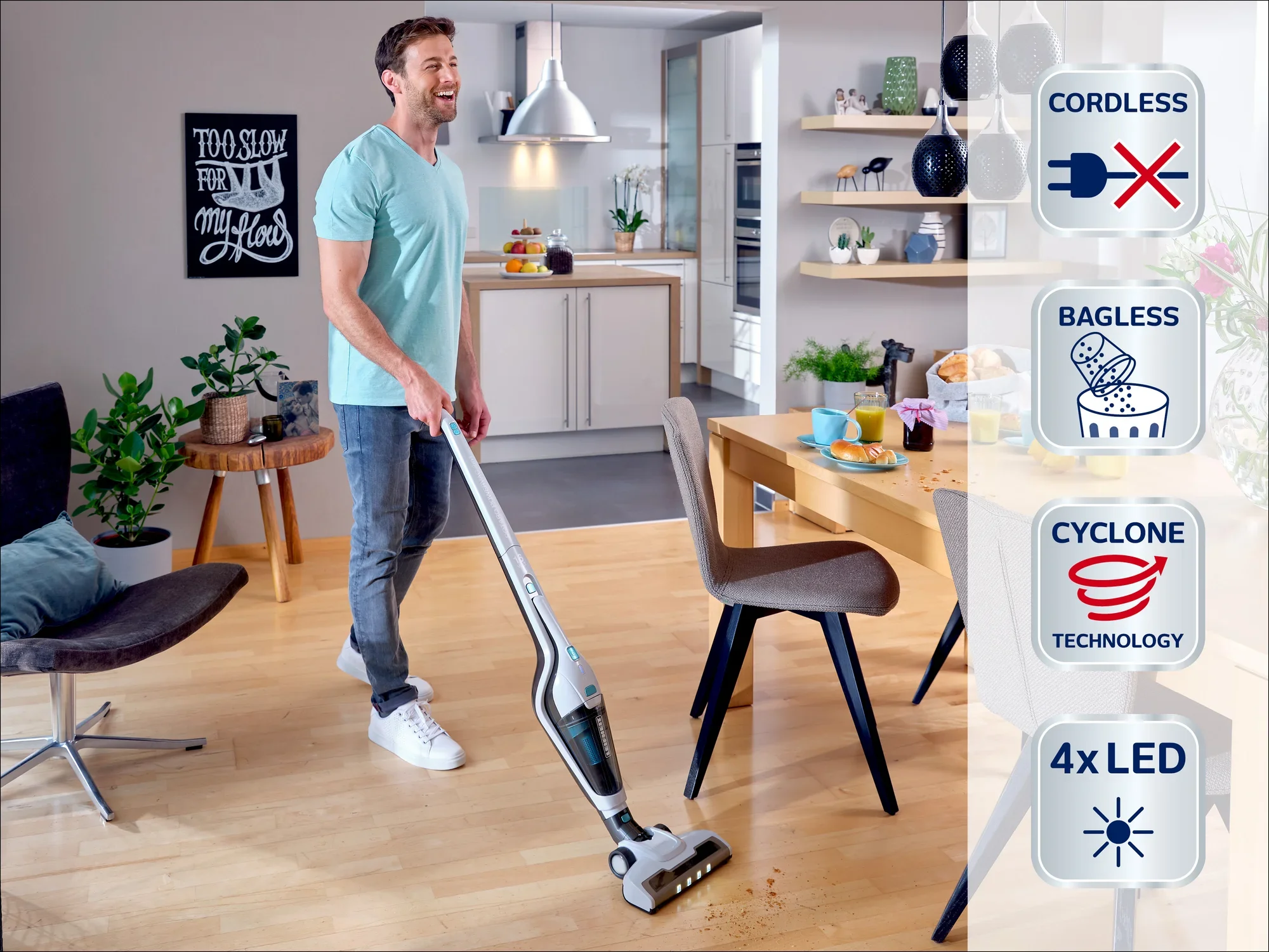 Un homme utilise un aspirateur sans fil et sans sac avec technologie cyclonique et 4 LED dans un salon moderne. L'aspirateur est léger et efficace.