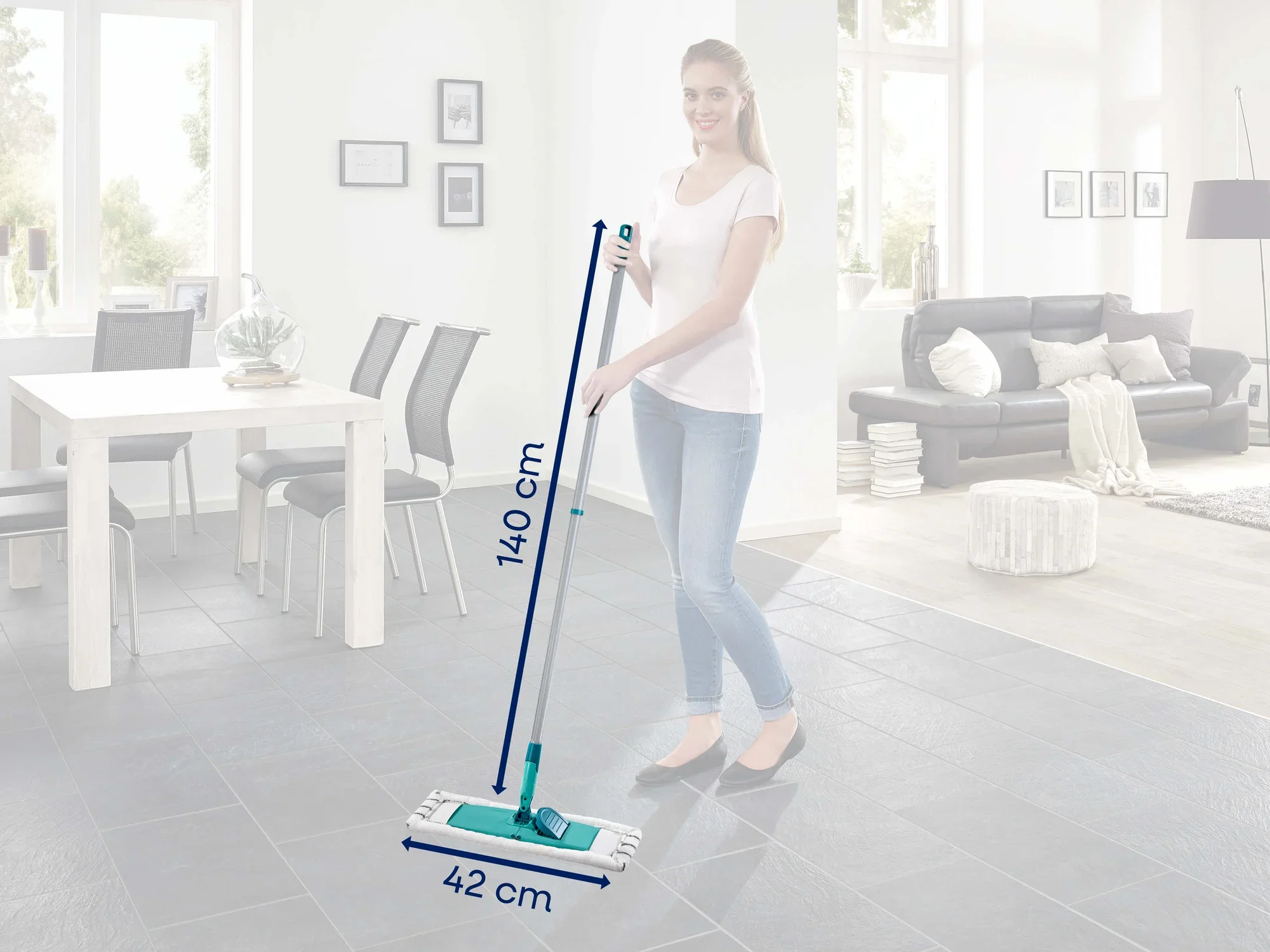Eine Frau steht in einem modernen Wohnzimmer und hält den Leifheit Bodenwischer Classic XL microfibre. Der Wischer hat eine Länge von 140 cm und eine Breite von 42 cm.