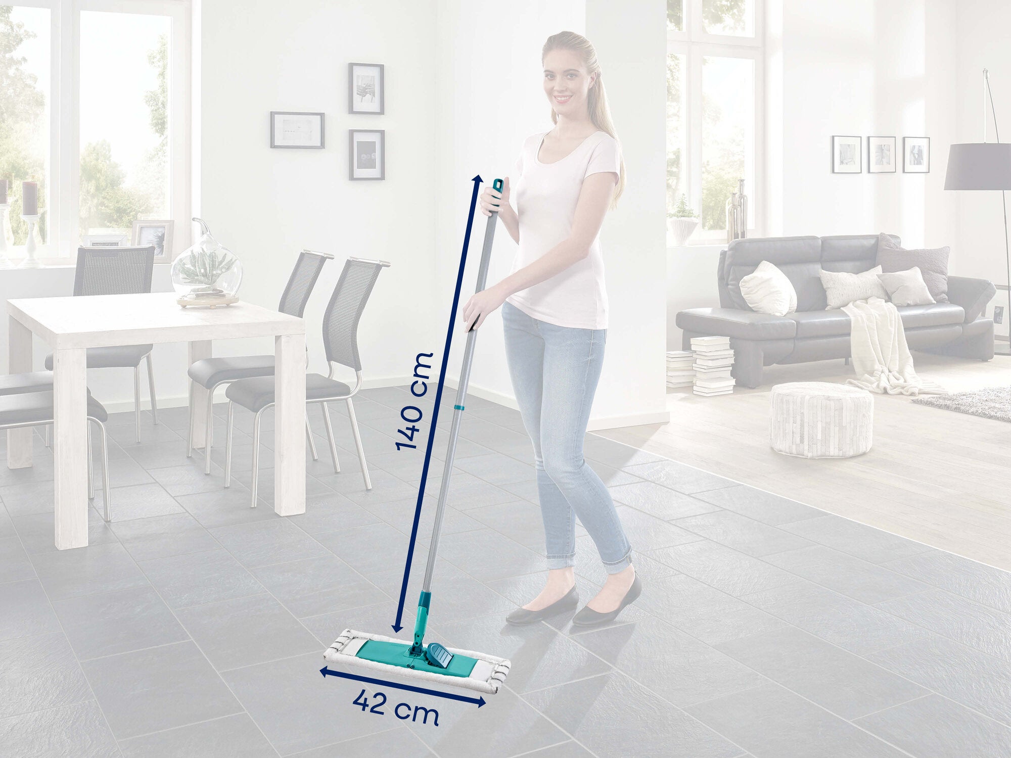 Eine Frau steht in einem modernen Wohnzimmer und hält den Leifheit Bodenwischer Classic XL microfibre. Der Wischer hat eine Länge von 140 cm und eine Breite von 42 cm.