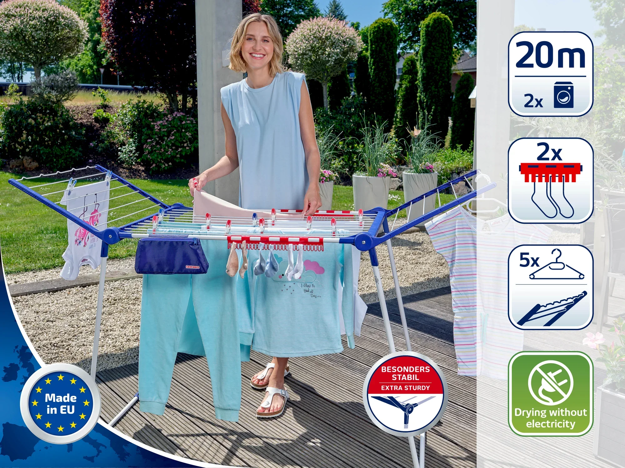 Een vrouw staat naast een vrijstaande droger in de tuin. De droger heeft een drooglengte van 20 meter, is bijzonder stabiel en maakt drogen zonder elektriciteit mogelijk. Ideaal voor milieuvriendelijk drogen.