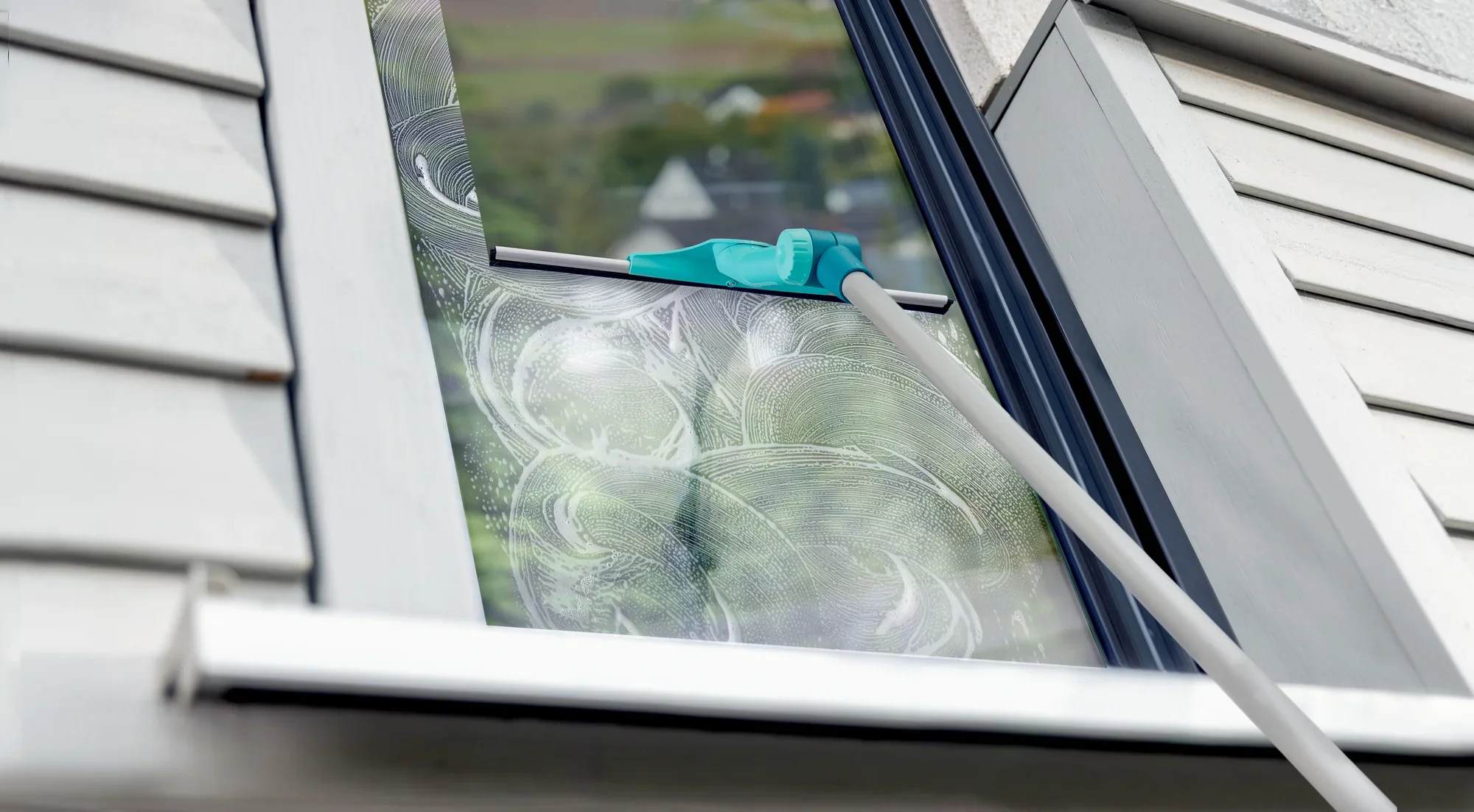 Myjka do okien z drążkiem teleskopowym WindowSlider 2in1 XL ProReach jest używana do mycia okien pod kątem. Niebieska głowica czyszcząca przesuwa się po szklanej powierzchni.