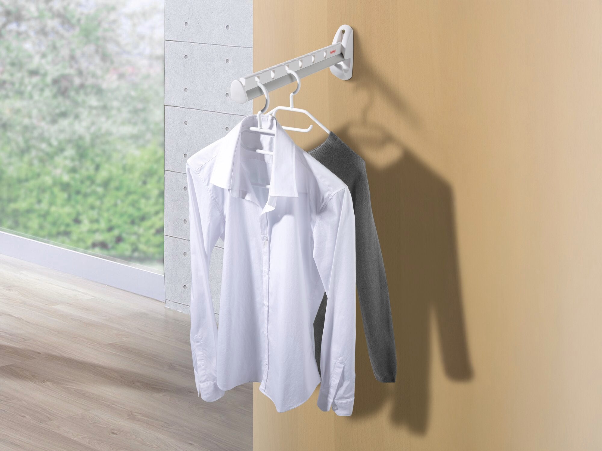 Wandkleiderlüfter Airette montiert an einer Wand mit zwei weißen Hemden auf Kleiderbügeln. Ideal für platzsparendes Trocknen und Lüften von Kleidung.