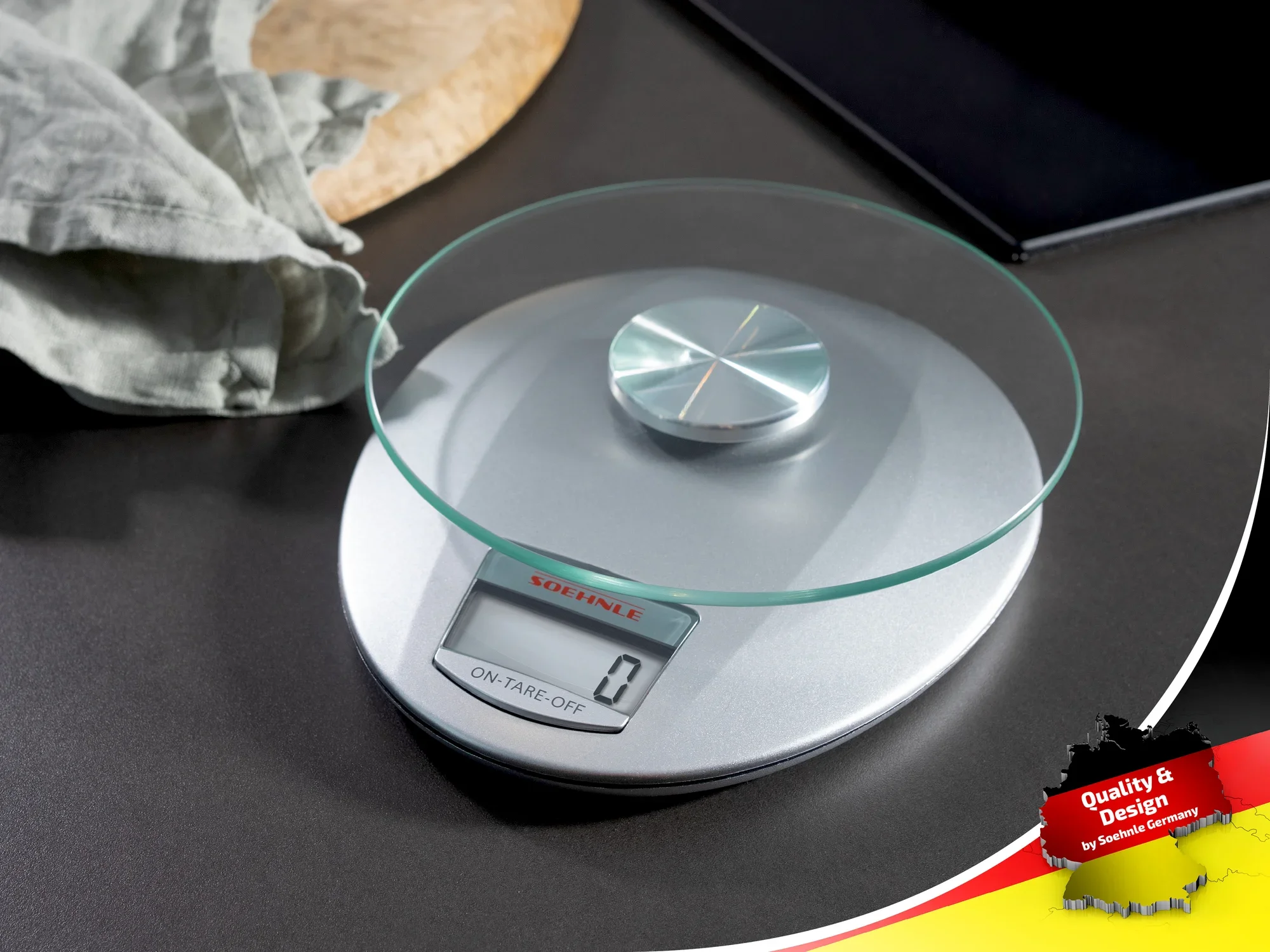 Cyfrowa waga kuchenna z okrągłym szklanym blatem i elementami ze stali nierdzewnej. Precyzyjny odczyt na cyfrowym wyświetlaczu. Idealna do dokładnych pomiarów w kuchni.