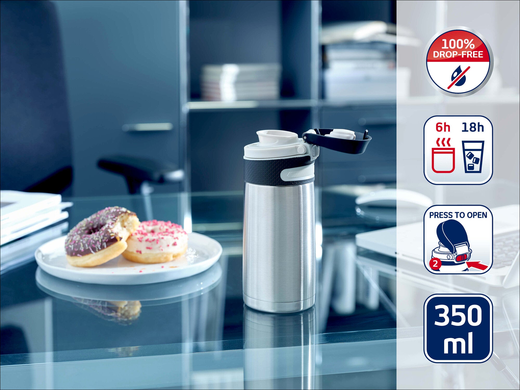 Leifheit Isolierbecher 350 ml aus Edelstahl steht geöffnet auf einem Glastisch im Büro neben einem Teller mit Donuts; Symbole zeigen 100 % auslaufsicher, 6 h warm, 18 h kalt und Deckel per Knopfdruck.