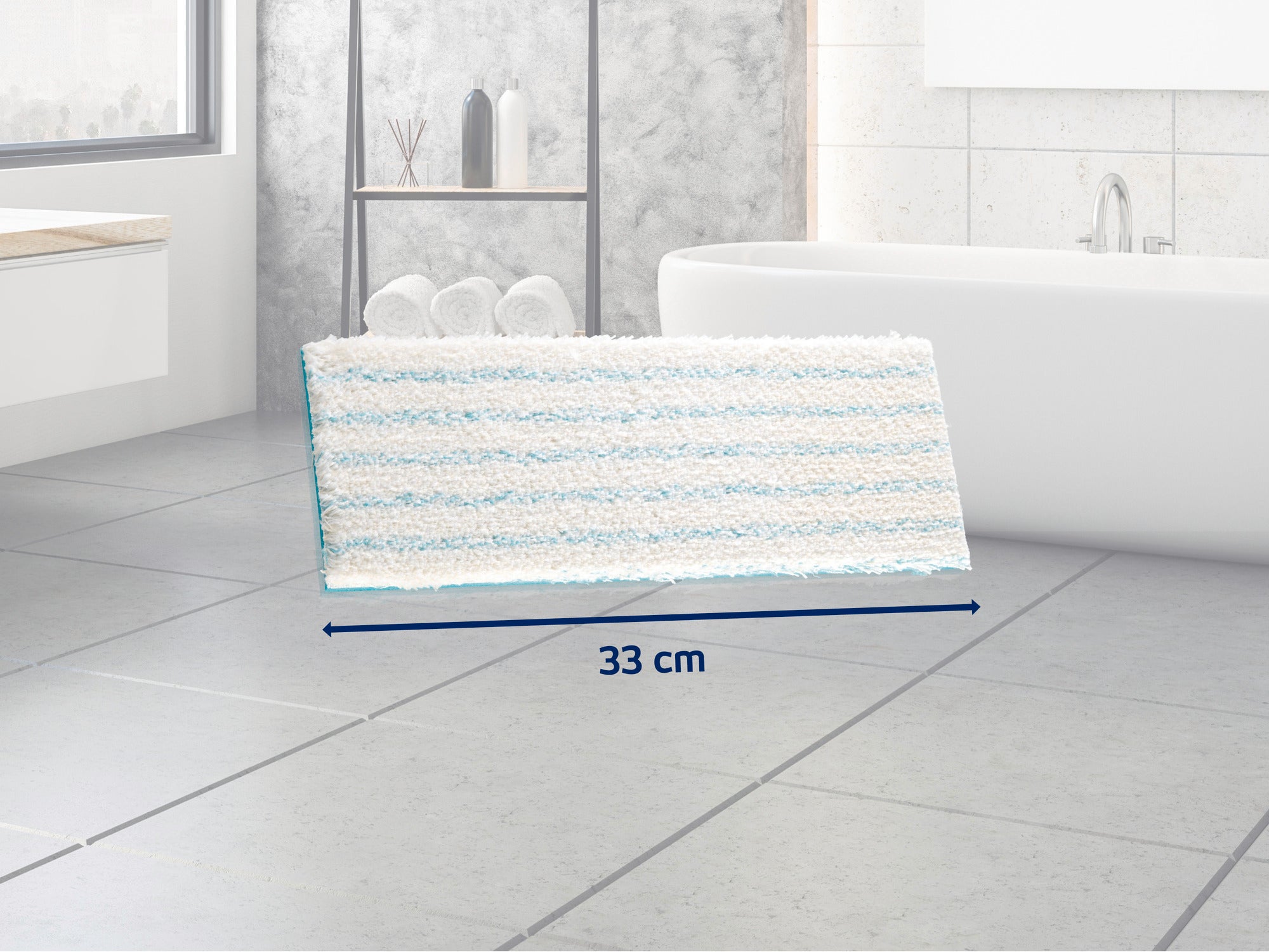 Prostokątny mop w niebiesko-białe paski leży na szarej podłodze wyłożonej kafelkami w nowoczesnej łazience. Mop ma 33 cm szerokości i idealnie nadaje się do mycia podłóg.