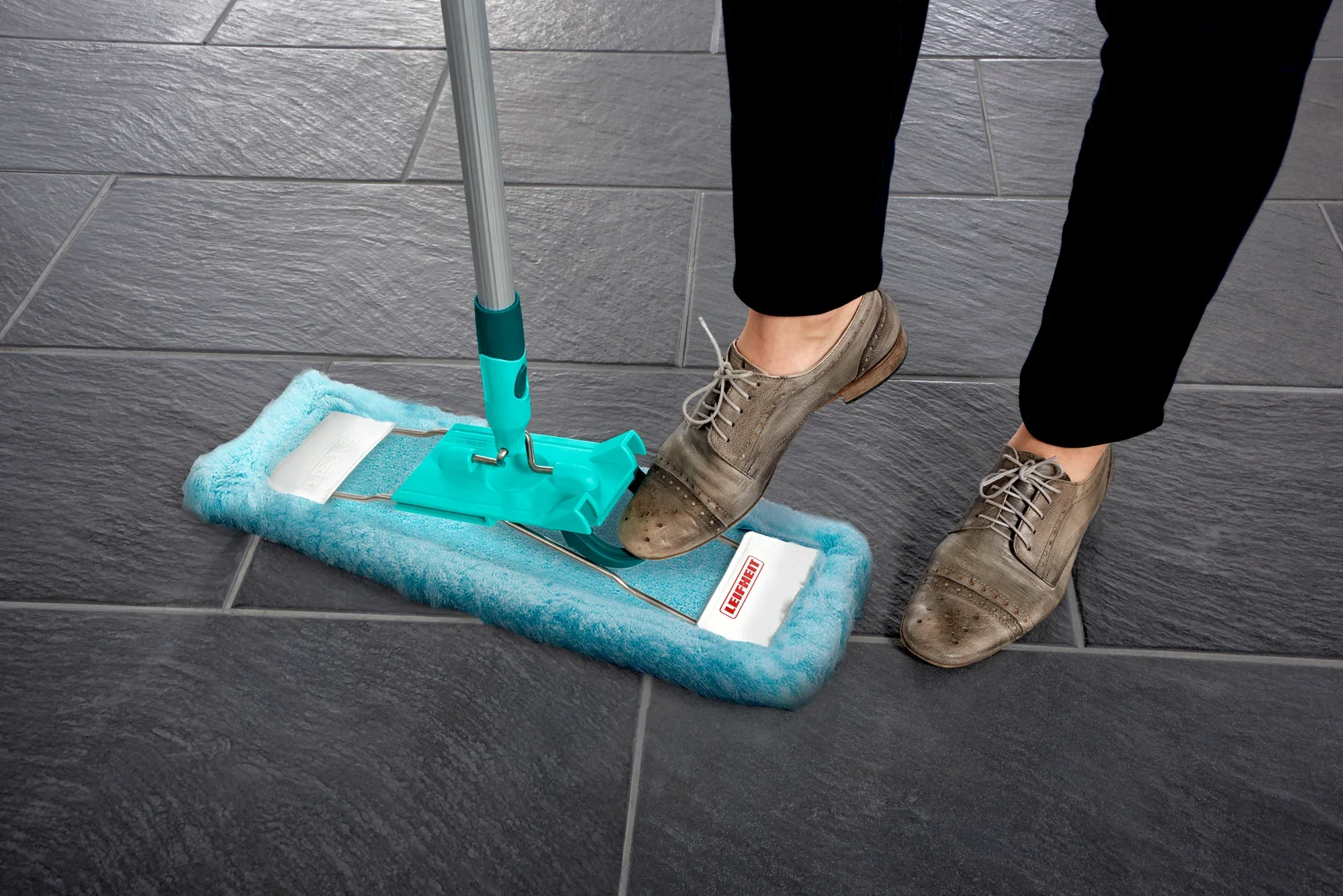 Housse Profi XL utilisée sur un sol carrelé foncé. La housse est turquoise et s'utilise avec un manche. Idéale pour un nettoyage en profondeur des grandes surfaces.