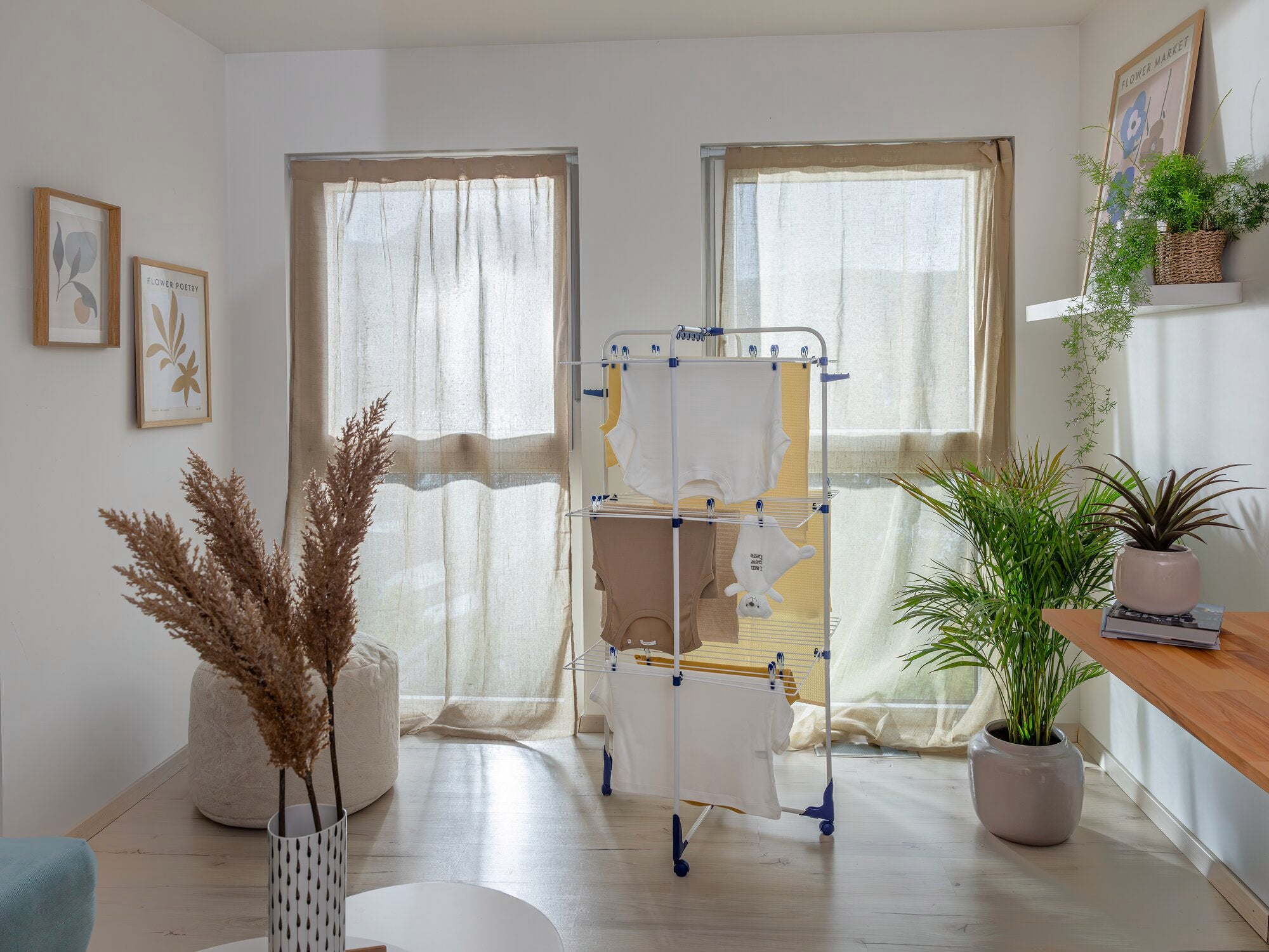 Un séchoir à tour Classic Tower 340 se trouve dans une pièce lumineuse et moderne. Le séchoir est chargé de linge et entouré de plantes.
