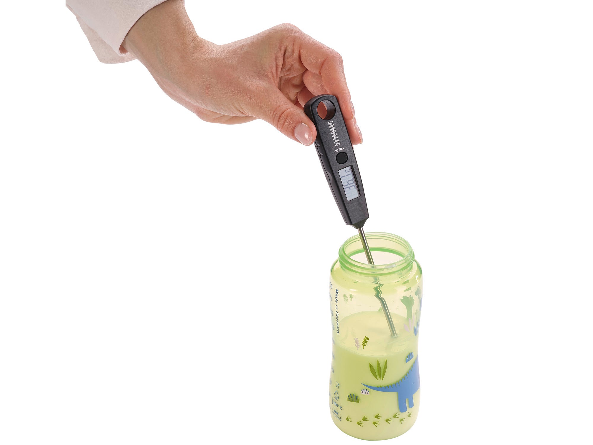 Eine Hand haelt ein digitales Thermometer in eine Babyflasche mit Milch, auf der ein blauer Dinosaurier abgebildet ist.