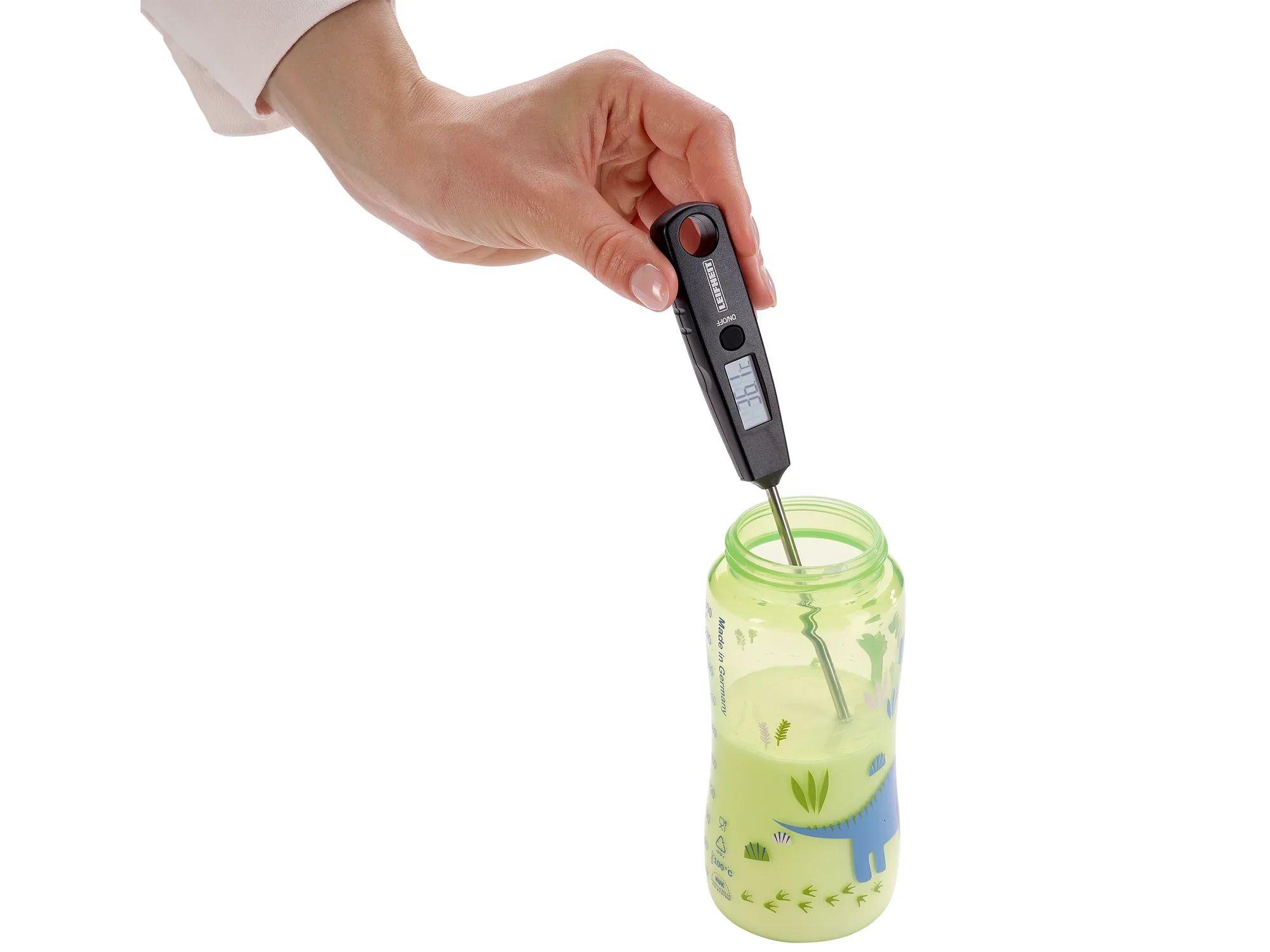 Jedna ręka trzyma uniwersalny termometr cyfrowy zanurzony w butelce z zieloną zawartością. Termometr mierzy temperaturę cieczy.