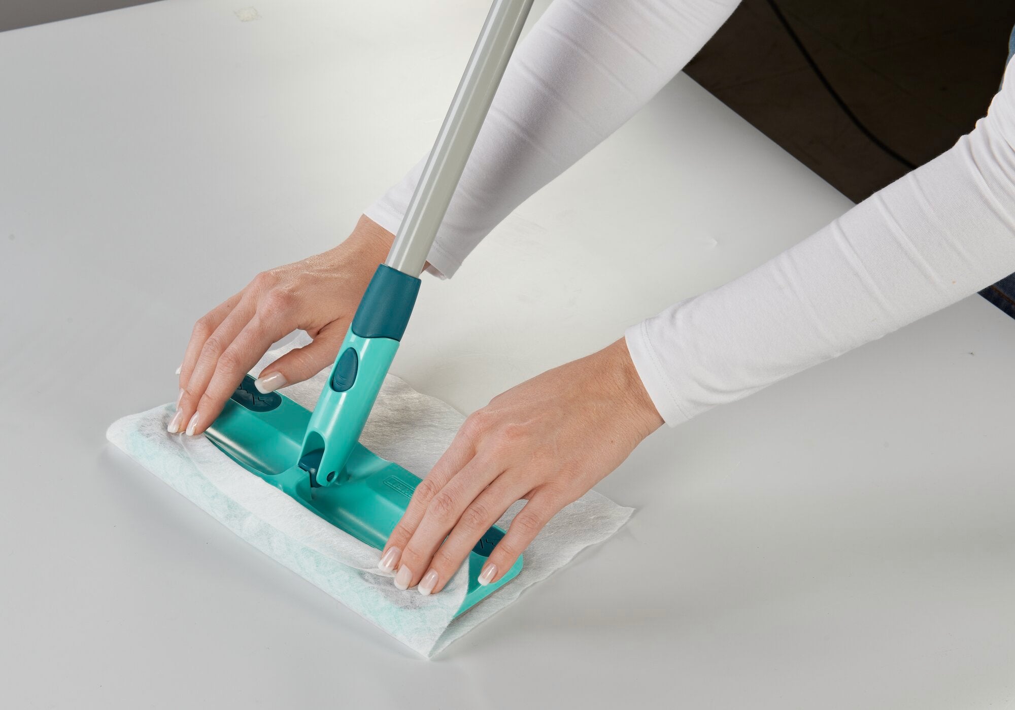 Bodenwischer Clean&Away wird auf einer glatten Oberfläche verwendet. Zwei Hände führen den Wischer über den Boden, um Schmutz und Staub effizient zu entfernen.