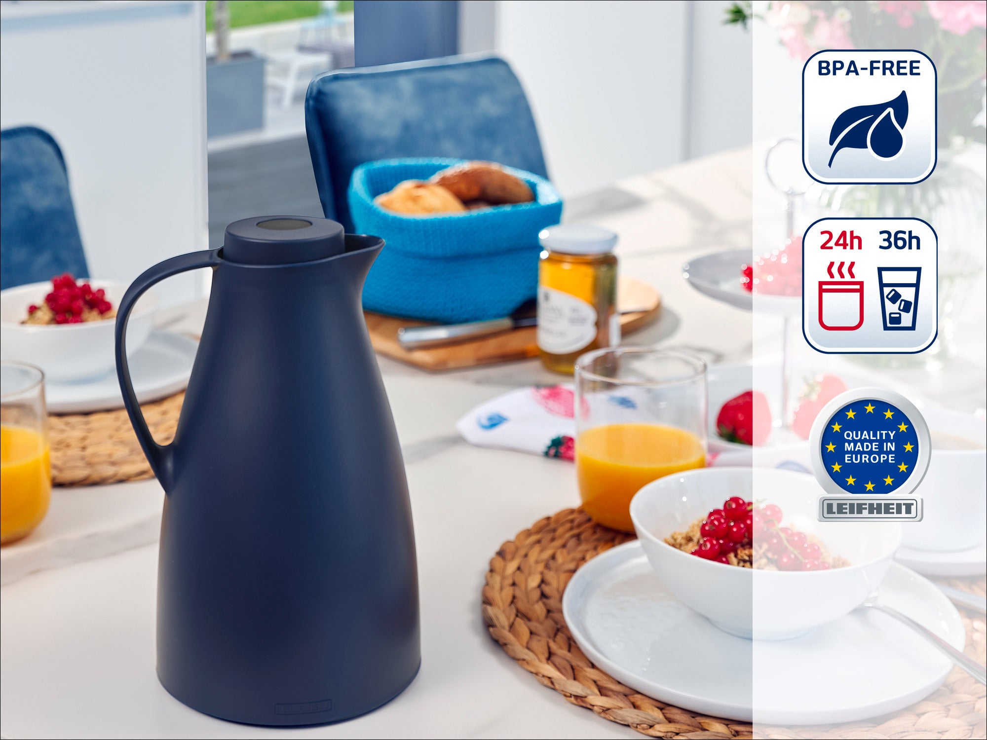 Une thermos noire est posée sur une table dressée pour le petit-déjeuner. À côté de la thermos, on aperçoit des bols contenant des céréales, du jus d'orange et de la confiture. La thermos est sans BPA et fabriquée en Europe.