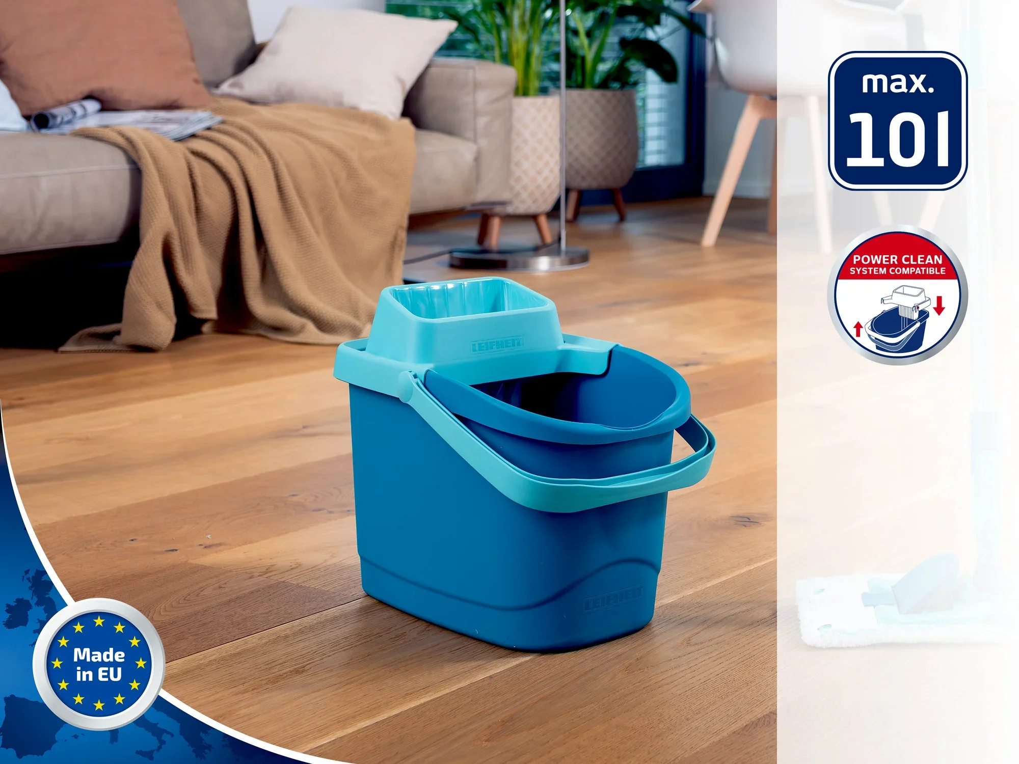 Un seau bleu avec une poignée est posé sur un parquet dans un salon. On aperçoit un canapé et des plantes à l'arrière-plan. Le seau a une capacité maximale de 10 litres.