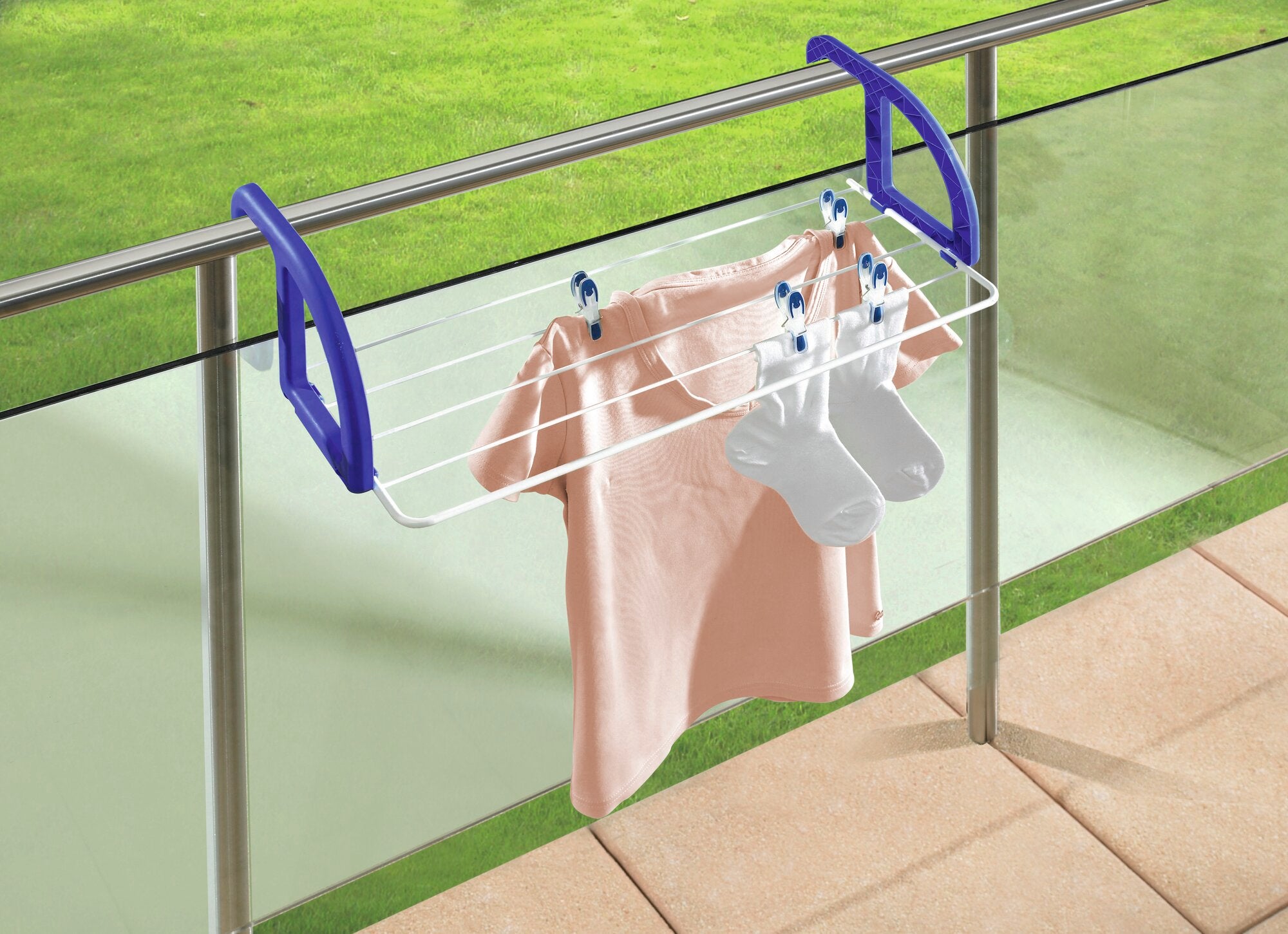 Ein Hängetrockner Classic 25 ist an einem Balkongeländer befestigt. Auf dem Trockner hängen ein rosa T-Shirt und weiße Socken. Der Trockner hat blaue Halterungen.
