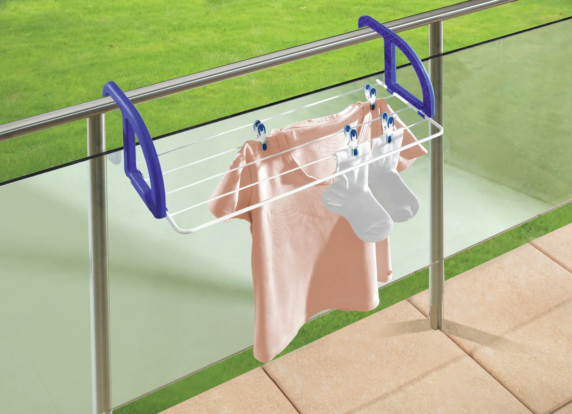 Suszarka wisząca Classic 25 jest przymocowana do balustrady balkonu. Na suszarce wisi różowa koszulka i białe skarpetki. Suszarka ma niebieskie wsporniki.