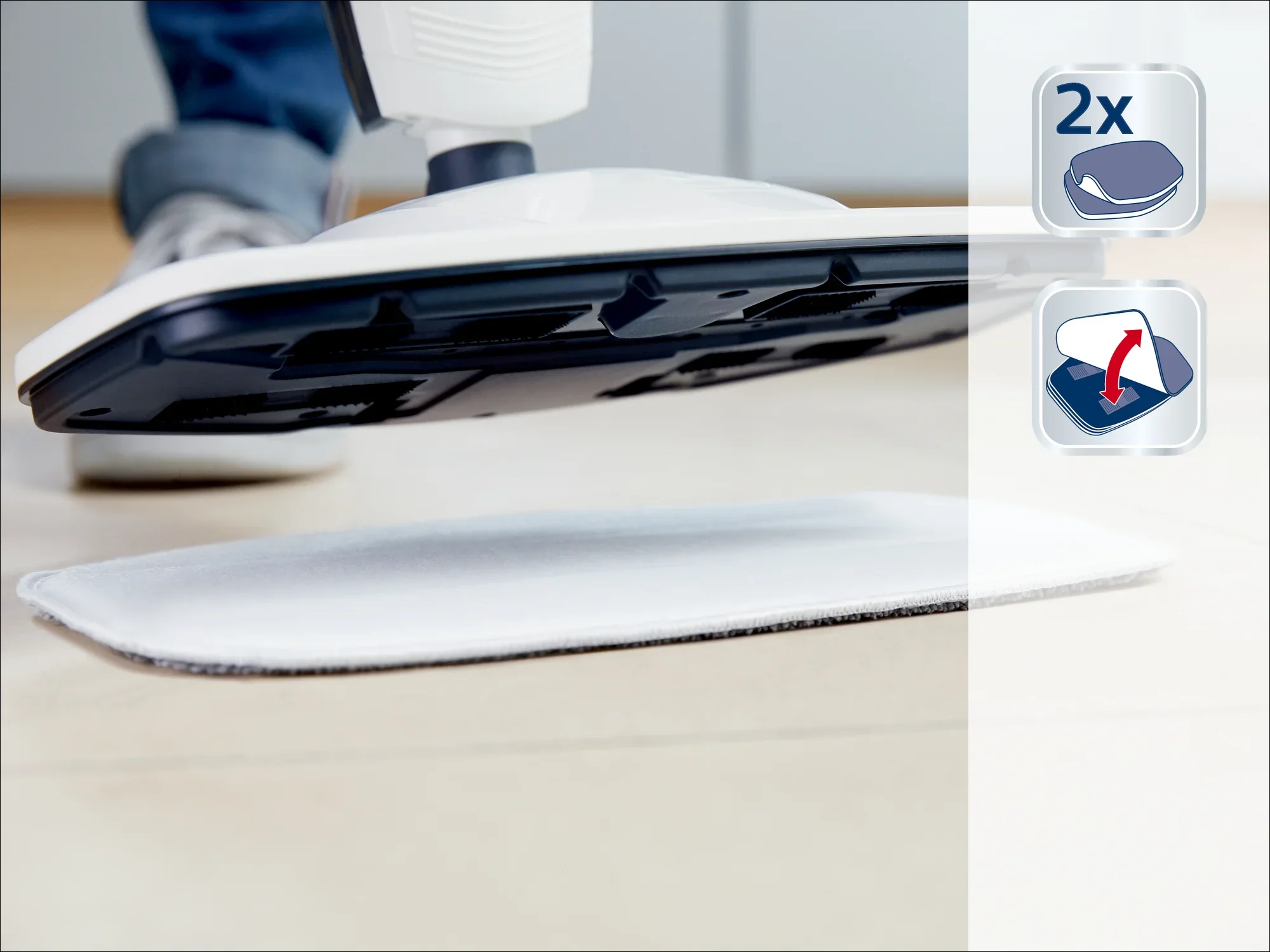 Limpiador a vapor con dos almohadillas de limpieza intercambiables. La imagen muestra el limpiador a vapor en acción sobre un revestimiento de suelo. Ideal para una limpieza a fondo.