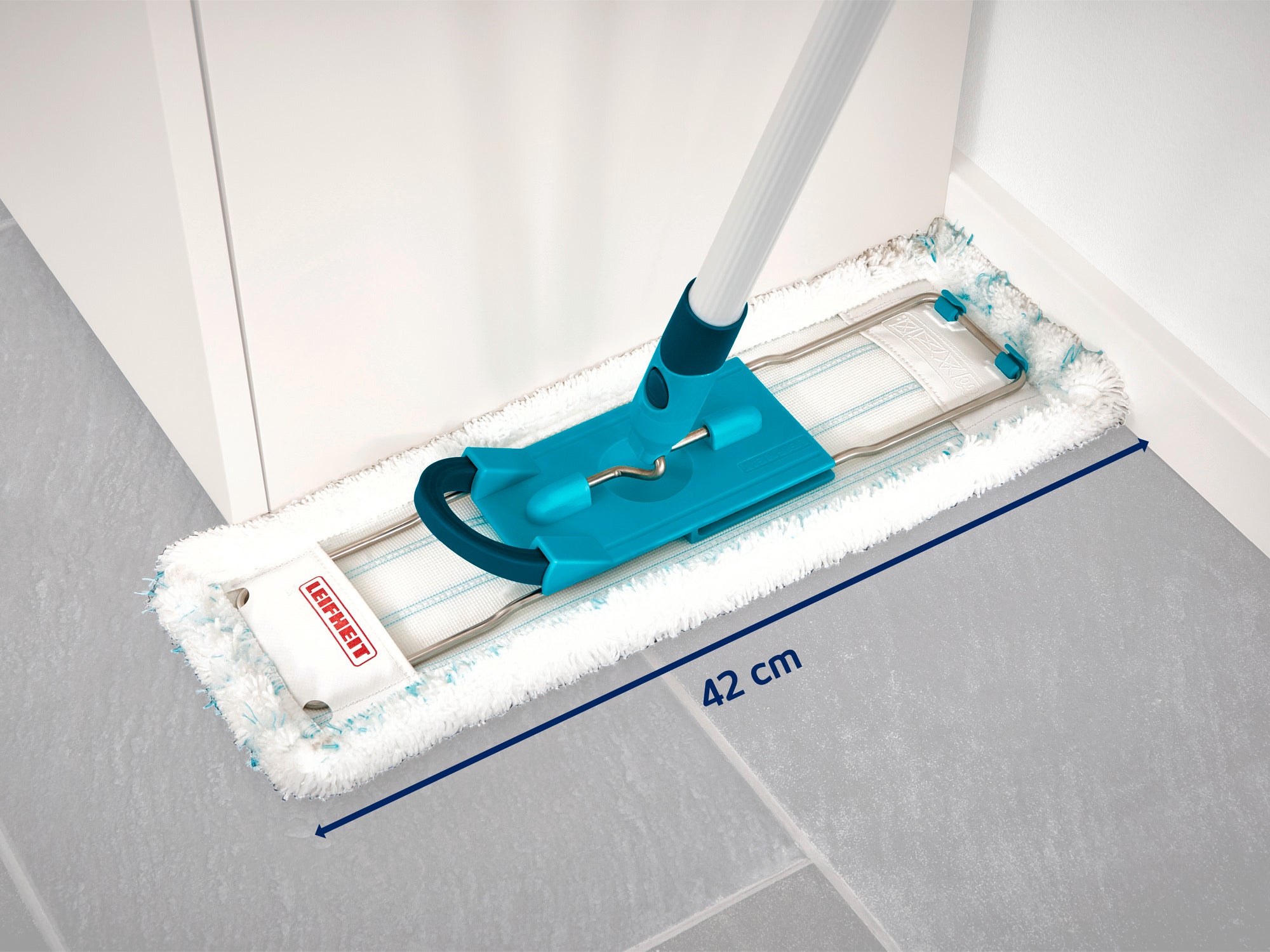 Ein Leifheit Bodenwischer mit einem 42 cm breiten Wischkopf liegt auf einem grauen Fliesenboden. Der Wischer hat einen türkisfarbenen Griff und ist ideal für die Reinigung von Ecken.