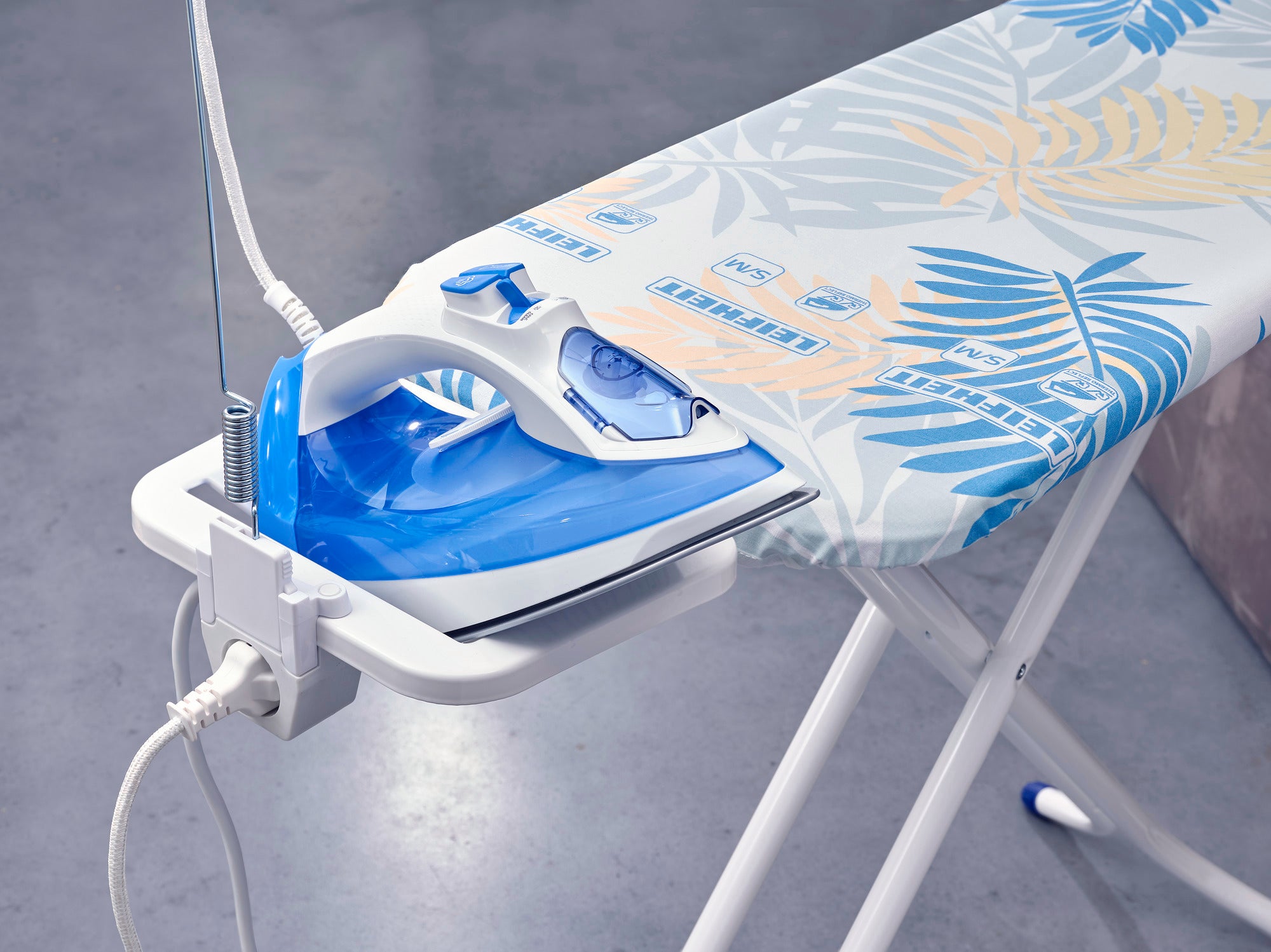 Bügeltisch Air Board M Compact Plus Jungle in Nahaufnahme. Der Tisch hat ein tropisches Design mit blauen und gelben Blättern und ein integriertes Bügeleisen.